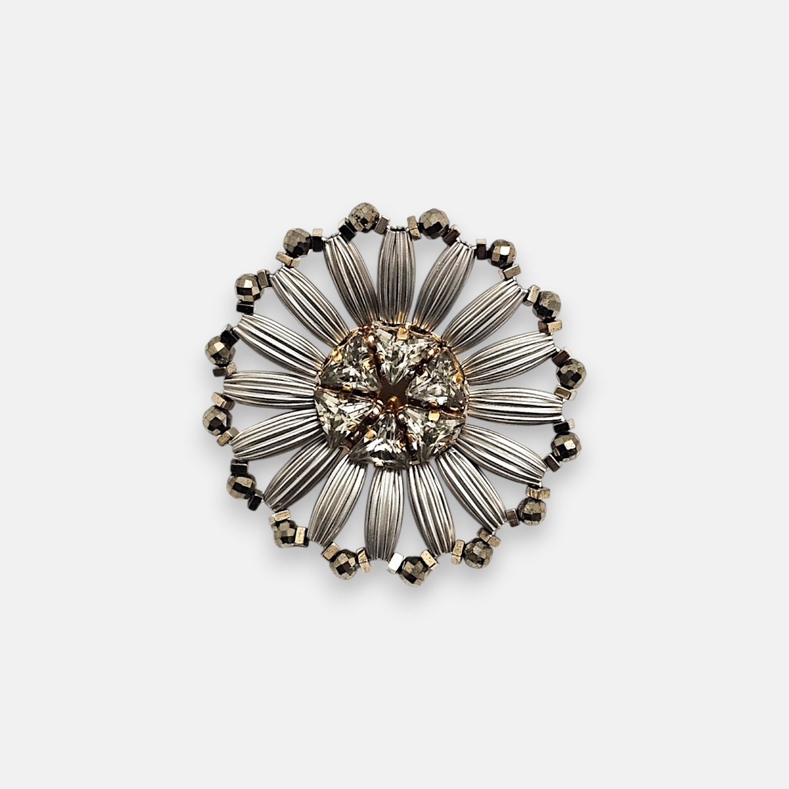Pin broche redondo Tataborello con diseño de flor calada en rutenio plateado y cristales centrales.