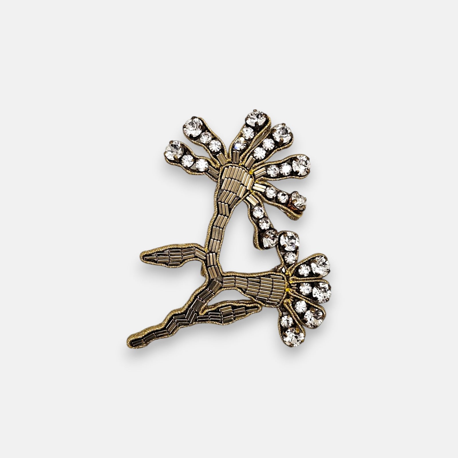 Broche artesanal Tataborello con silueta de rama bordada en canutillos bronce y remates de cristales brillantes.