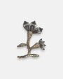 Broche artesanal de solapa Tataborello con silueta de flor y rama bordada en canutillos claros y pétalos estriados de rutenio oscuro.