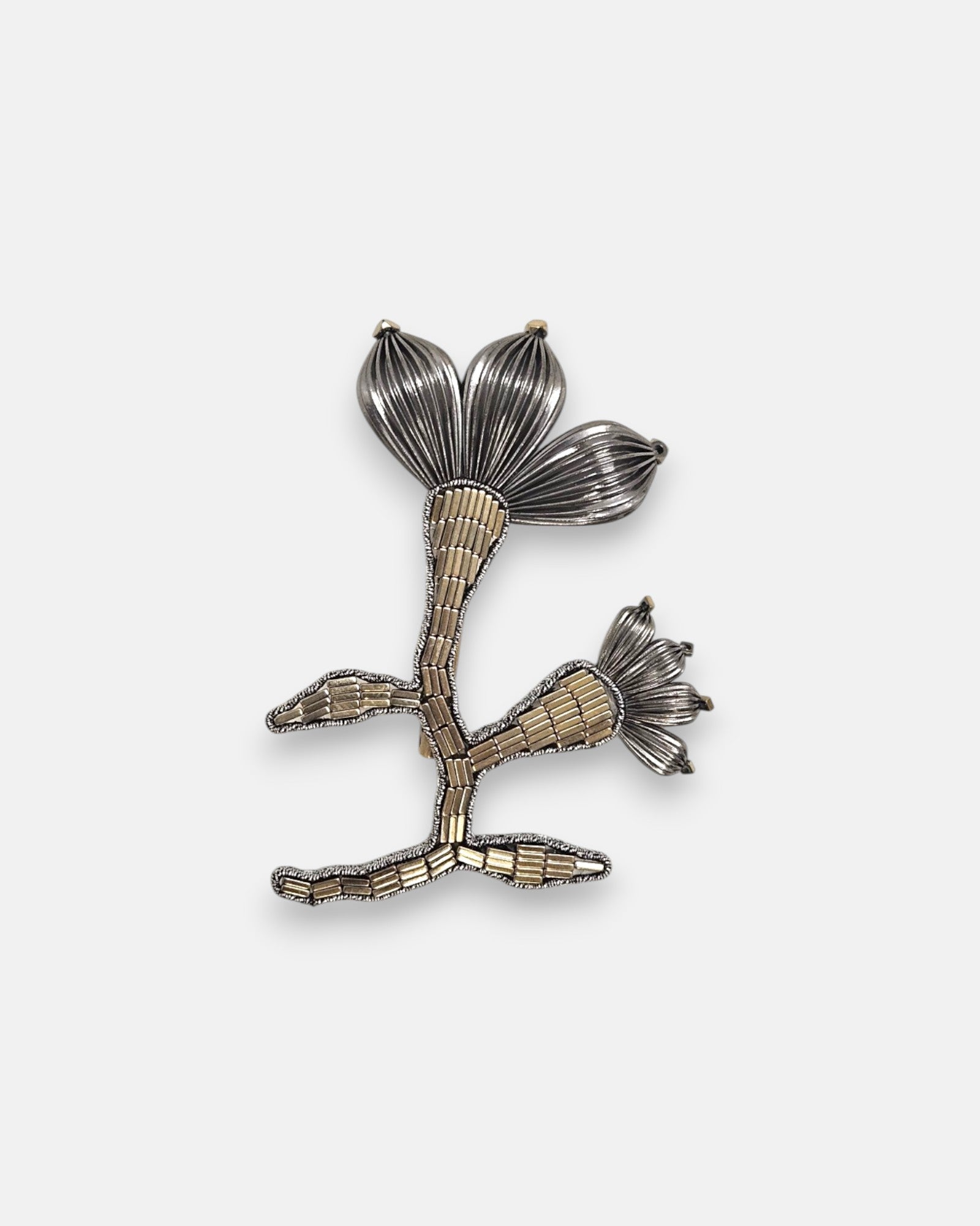 Broche artesanal de solapa Tataborello con silueta de flor y rama bordada en canutillos claros y pétalos estriados de rutenio oscuro.