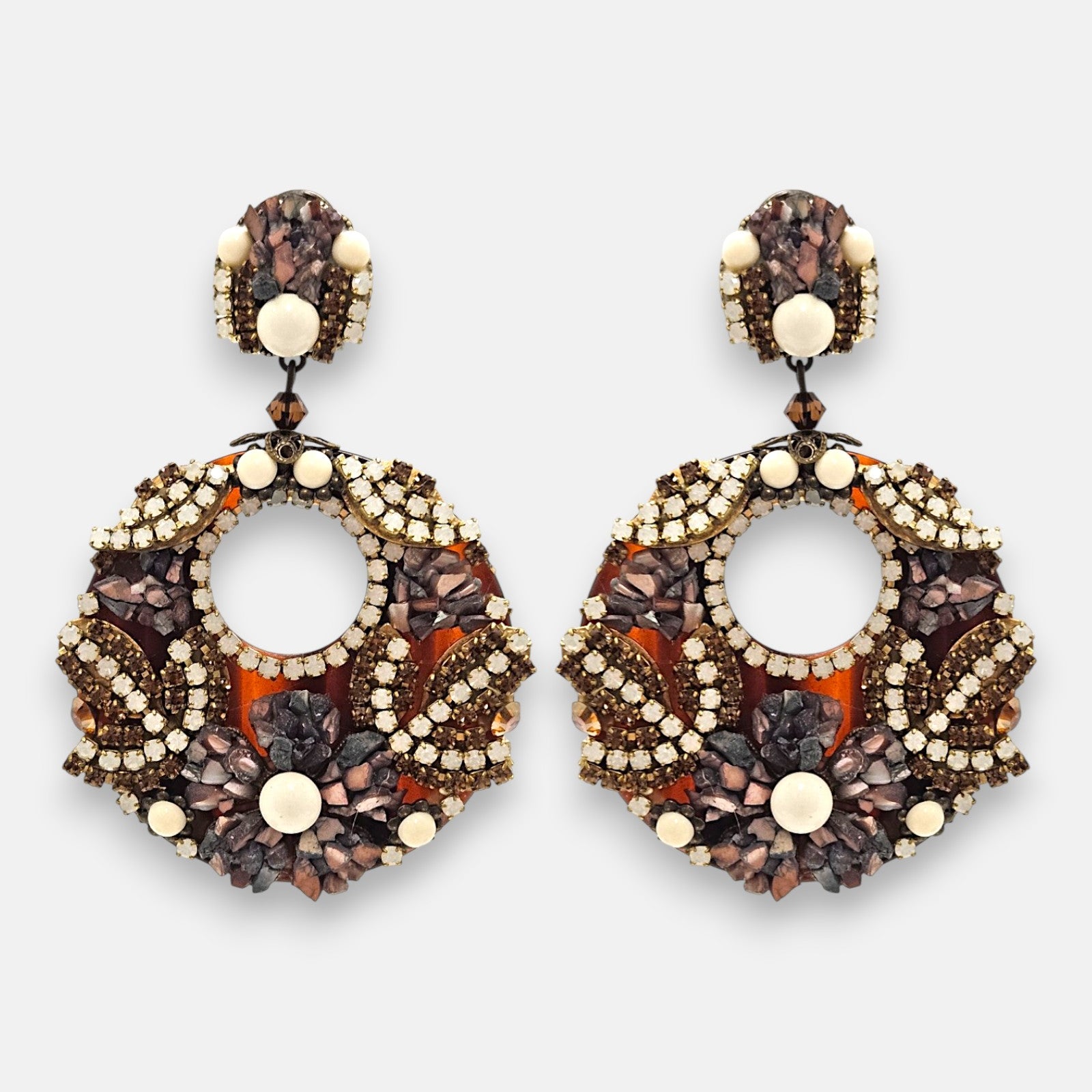Pareja de pendientes grandes de fiesta en forma de aro Mosaico de Ámbar de Dublos, mostrando su base de carey decorada con strass, piedras en tonos tierra y cuentas marfil.