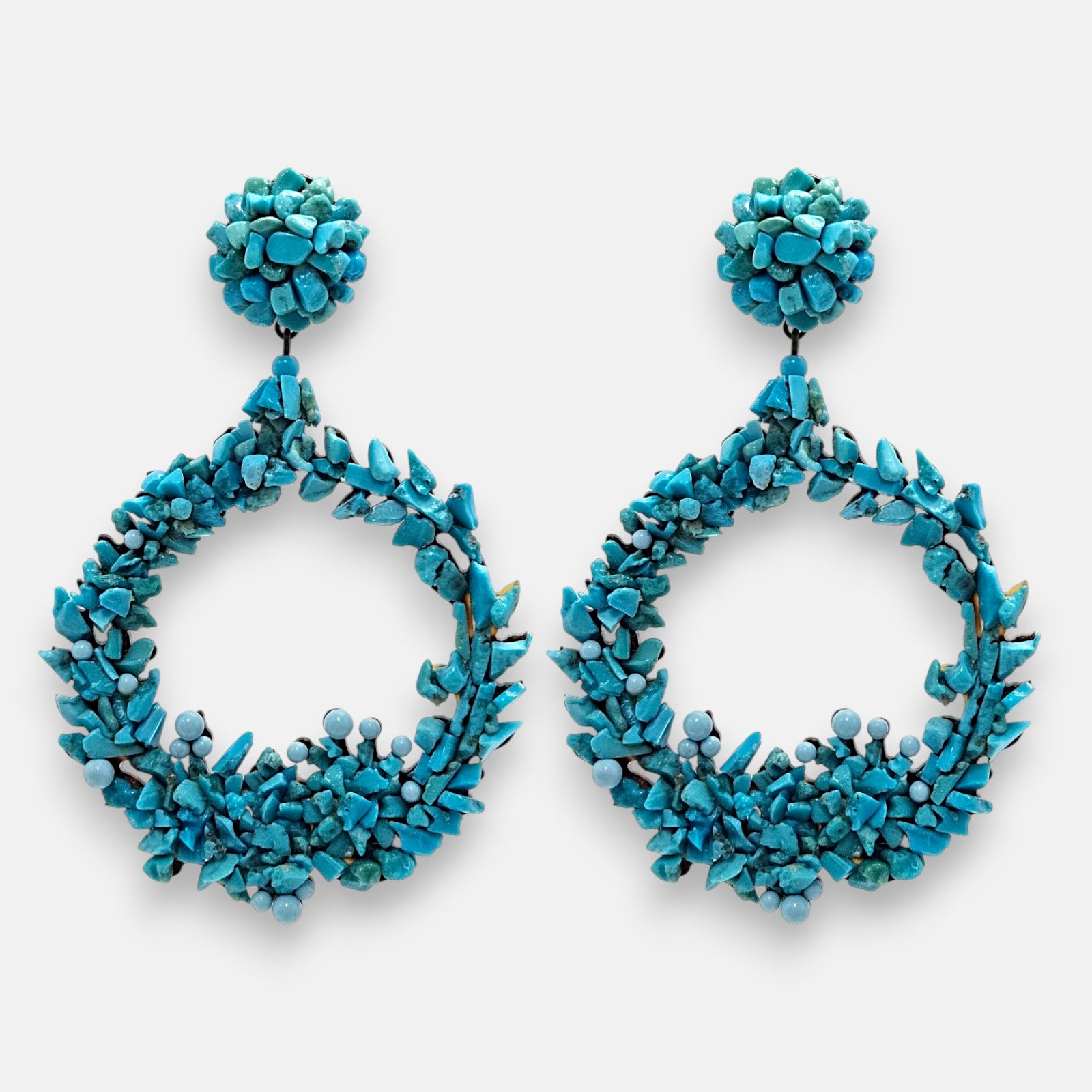 Pareja de pendientes de fiesta grandes en forma de aro abierto Corona de Cícladas de Dublos, mostrando su mosaico texturizado de cuentas y fragmentos en azul claro turquesa.