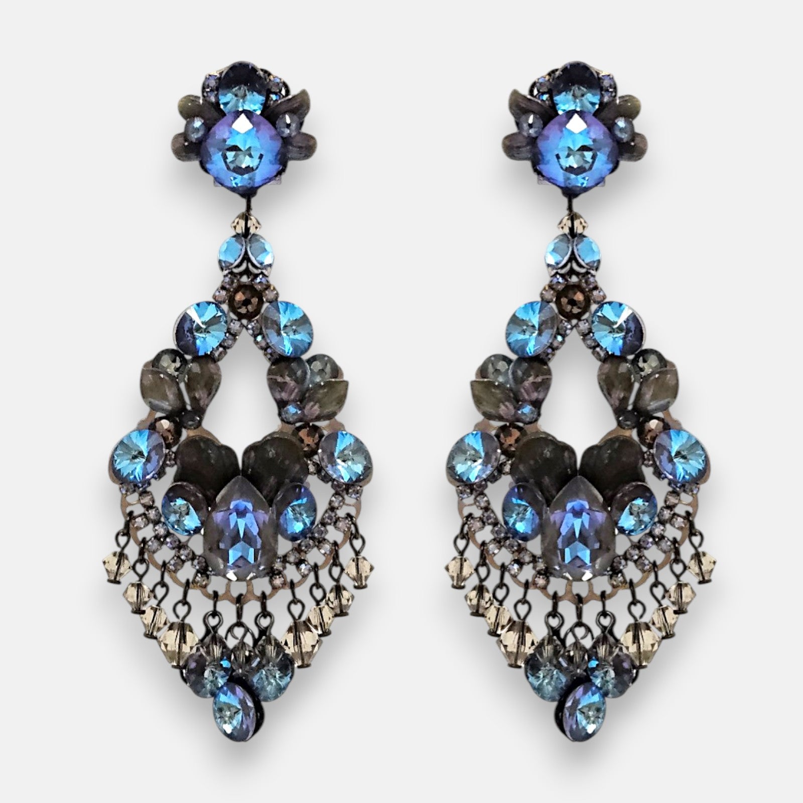 Pareja de pendientes de fiesta grandes Destello del Bósforo de la firma Dublos, mostrando su diseño de lágrima calada con cristales azul zafiro, strass y flecos colgantes.