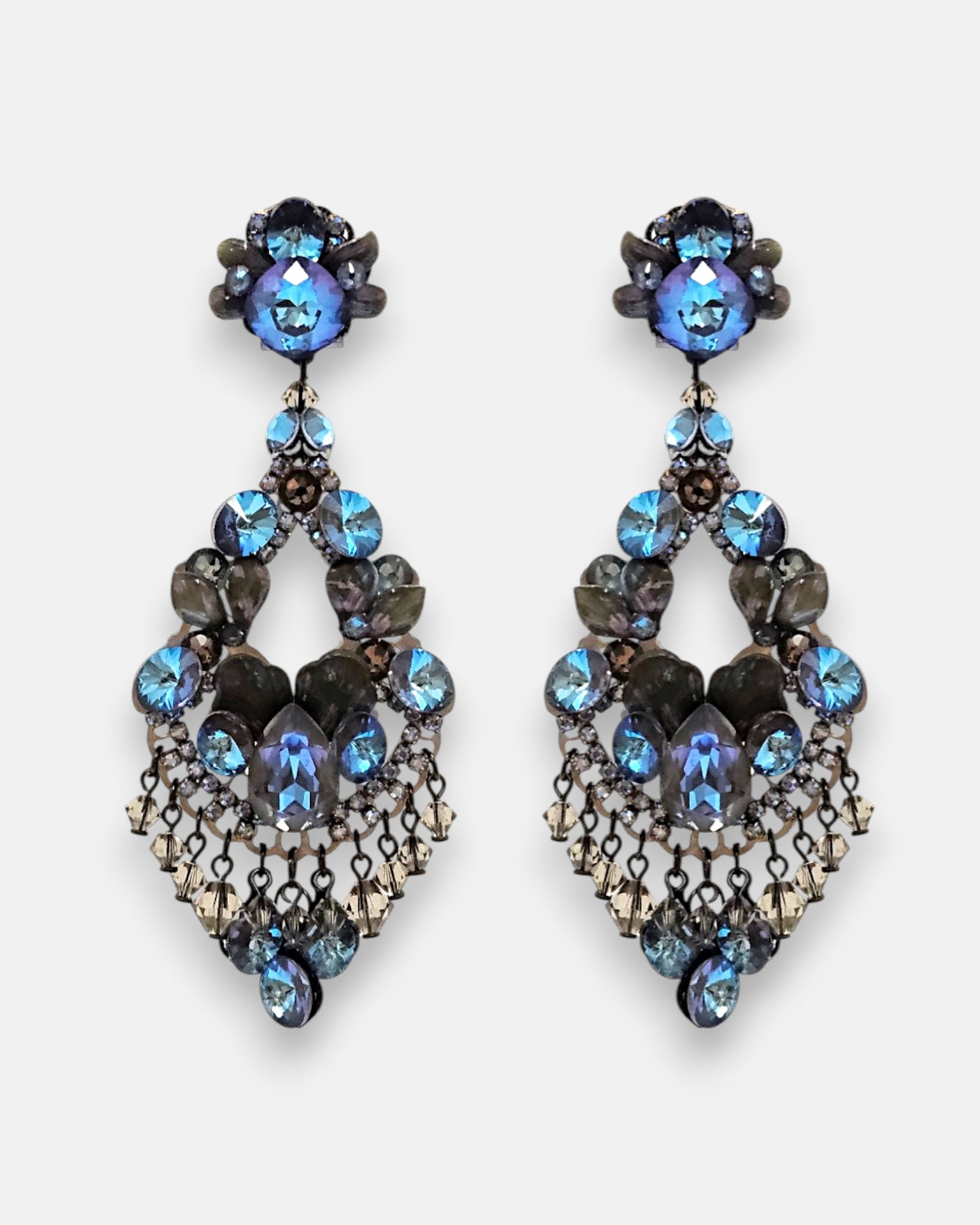 Pareja de pendientes de fiesta grandes Destello del Bósforo de la firma Dublos, mostrando su diseño de lágrima calada con cristales azul zafiro, strass y flecos colgantes.
