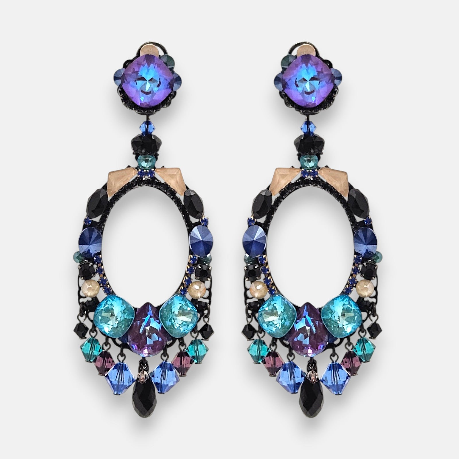Pareja de pendientes grandes de aro ovalado Océano Índigo de la firma Dublos, mostrando su pedrería en azul turquesa, violeta y flecos colgantes de cristales.