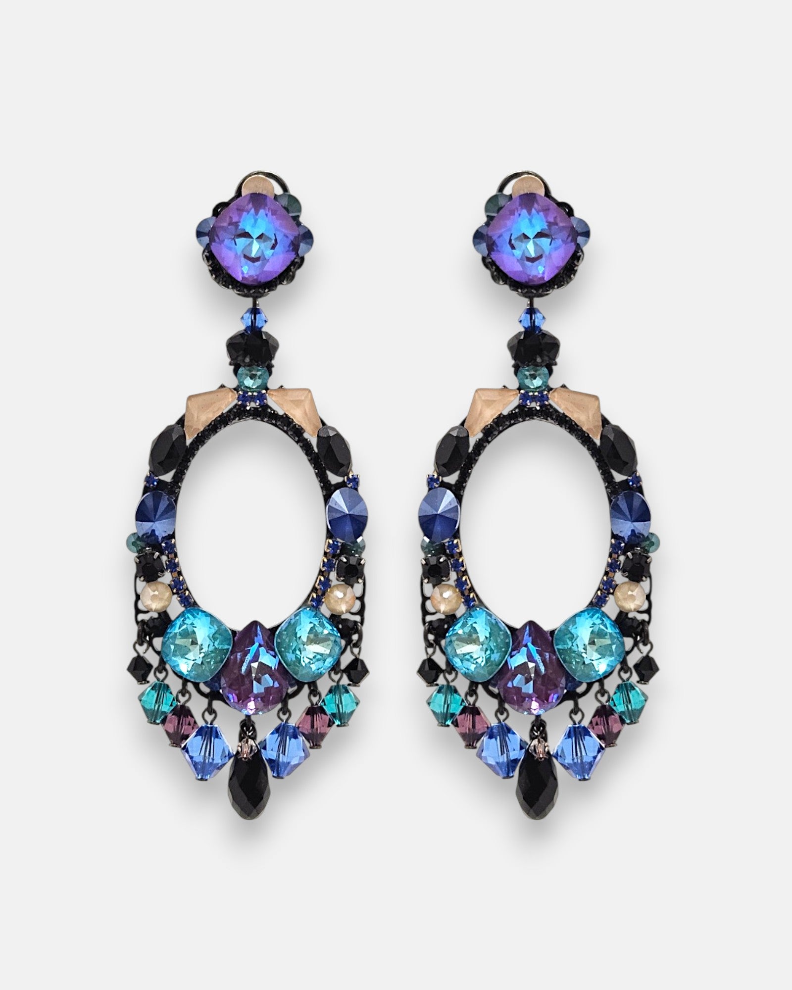 Pareja de pendientes grandes de aro ovalado Océano Índigo de la firma Dublos, mostrando su pedrería en azul turquesa, violeta y flecos colgantes de cristales.