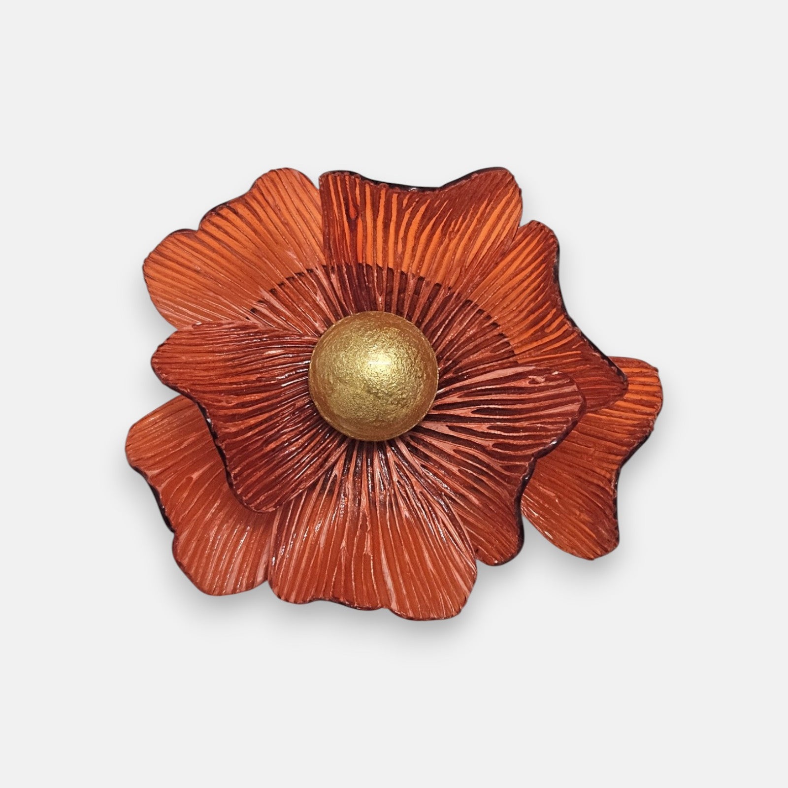 broche de flor de Ciléa Paris sobre fondo neutro, apreciando su diseño de pétalos estriados color naranja terracota con pistilo central dorado.