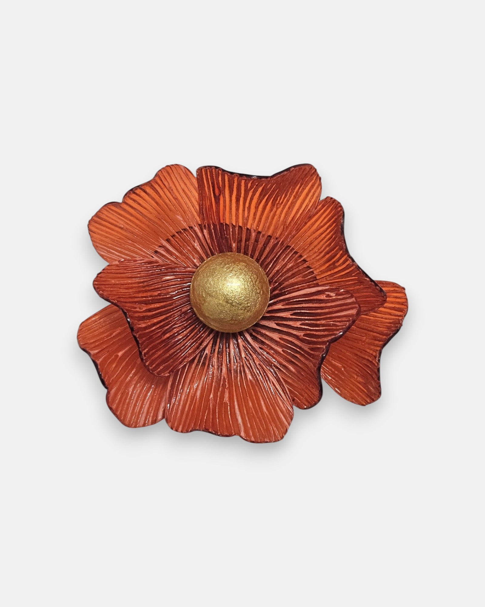broche de flor de Ciléa Paris sobre fondo neutro, apreciando su diseño de pétalos estriados color naranja terracota con pistilo central dorado.