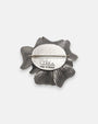 reverso del broche artesanal, detallando el pasador metálico de aguja para la sujeción y la firma labrada de la marca "Ciléa Made in France".