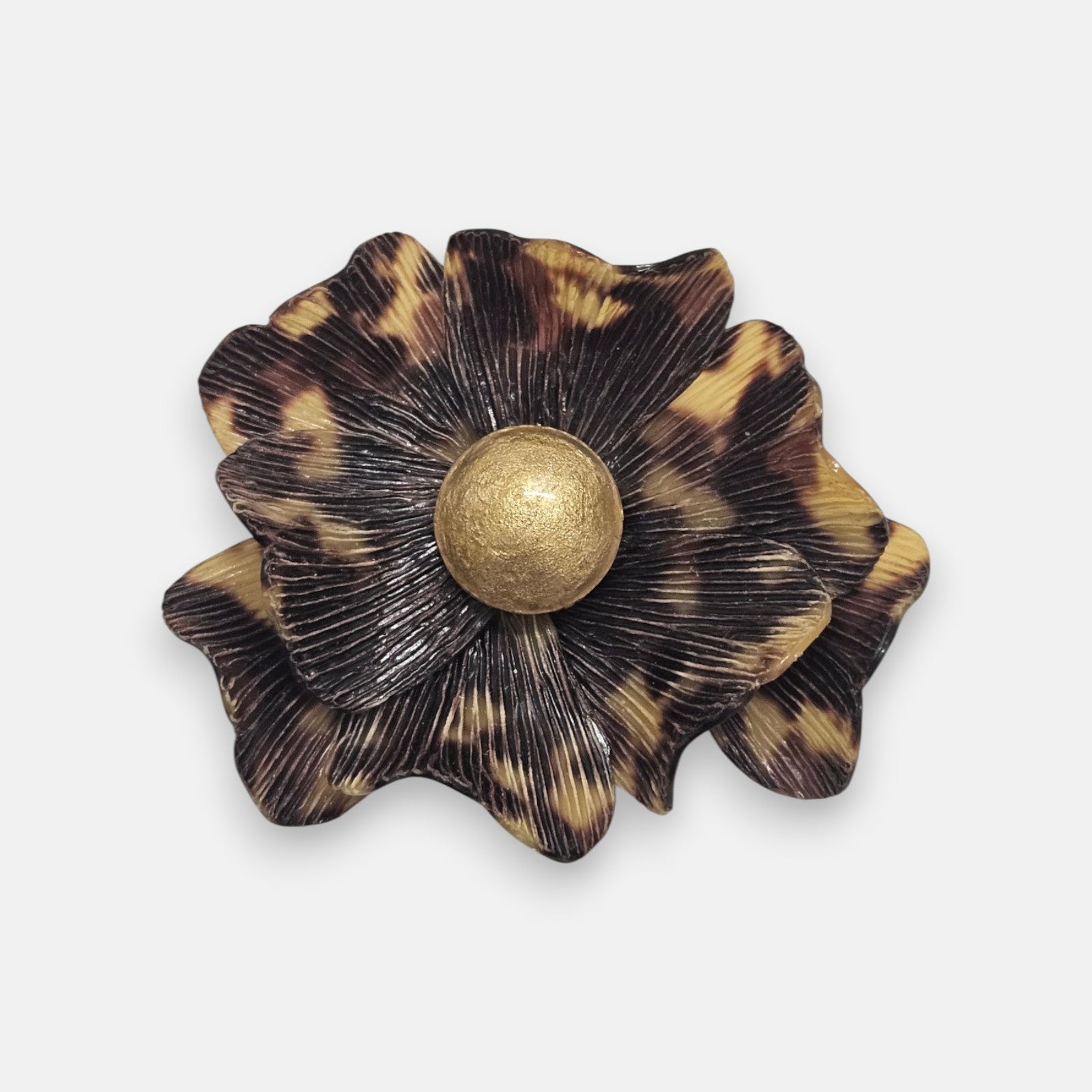 broche de flor de Ciléa Paris sobre fondo neutro, apreciando su diseño de pétalos estriados con patrón de carey en marrón y negro con centro dorado.