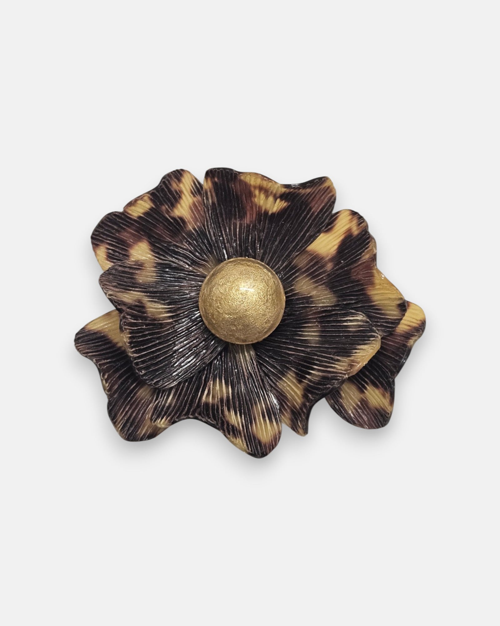broche de flor de Ciléa Paris sobre fondo neutro, apreciando su diseño de pétalos estriados con patrón de carey en marrón y negro con centro dorado.