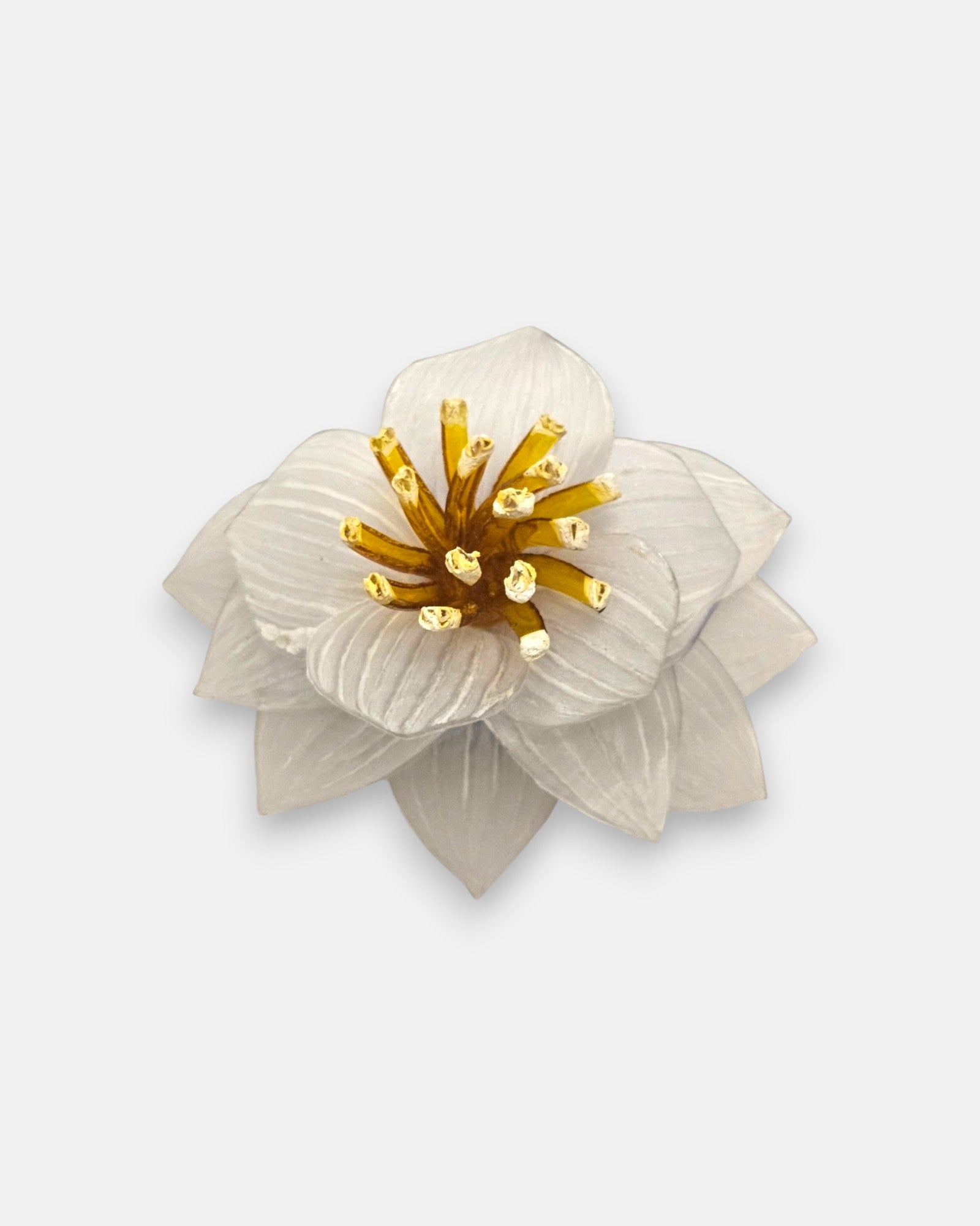 broche de loto blanco de frente en primer plano sobre fondo neutro, detallando sus pétalos estriados translúcidos y el centro con pistilos color ámbar.