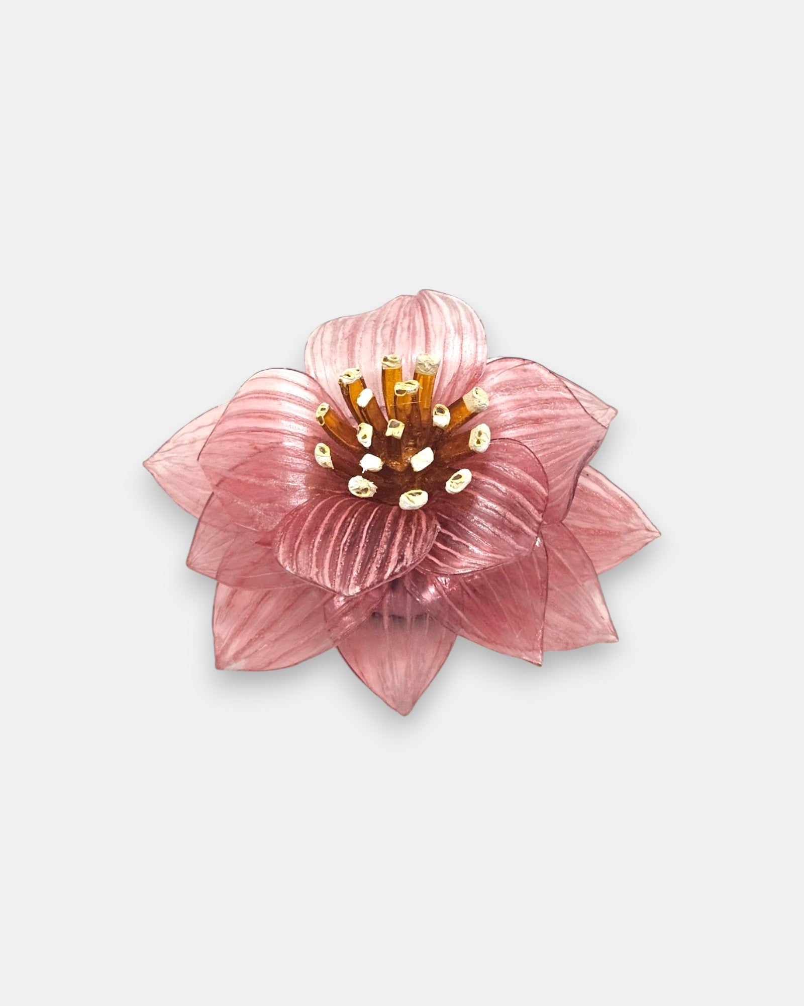 broche de flor de loto de Ciléa Paris sobre fondo claro, apreciando su juego de capas de pétalos estriados color rosa viejo y su centro ámbar.