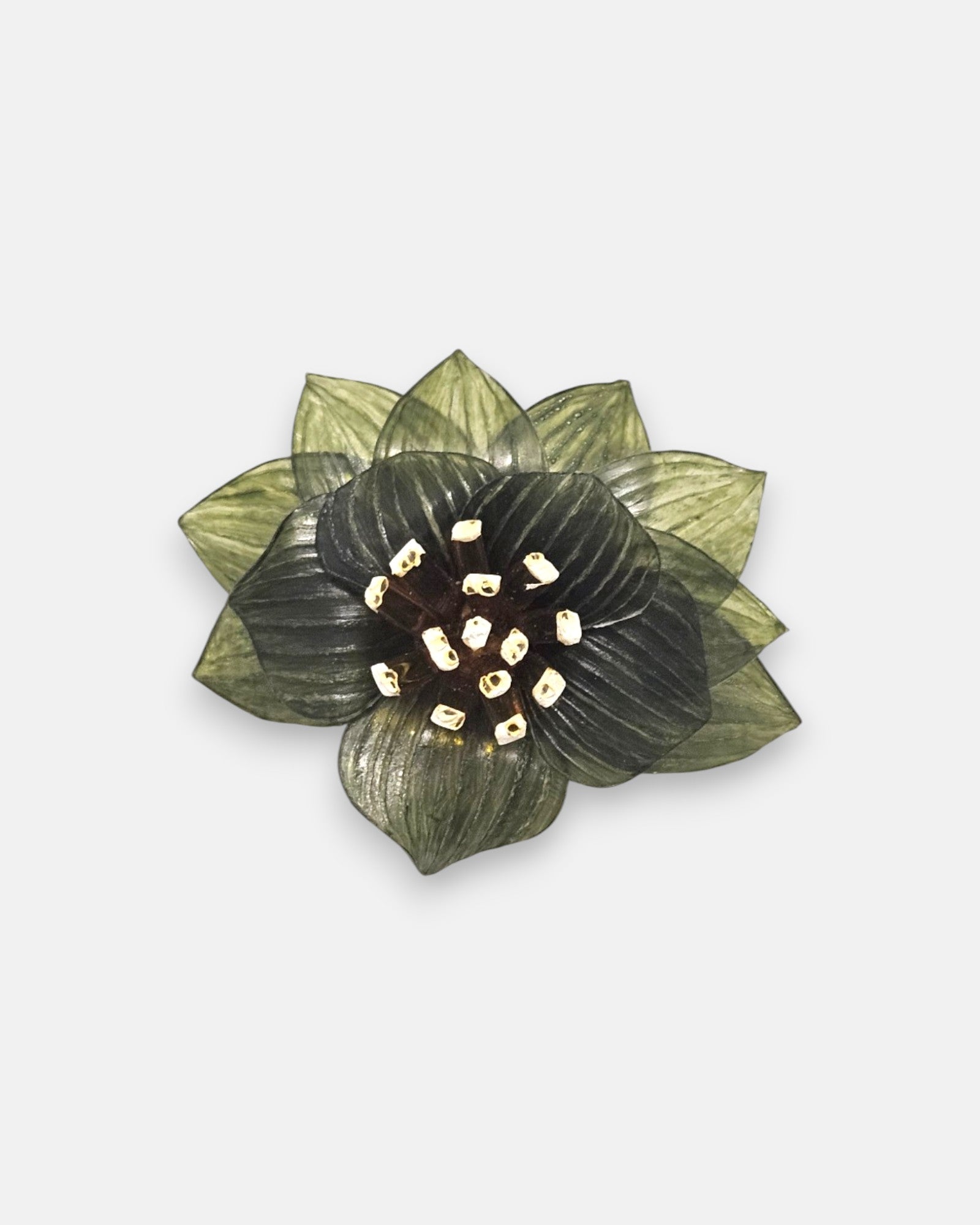 broche con forma de flor de loto de Ciléa Paris sobre fondo claro, apreciando la disposición de sus capas en resina translúcida verde oliva y su centro de pistilos.