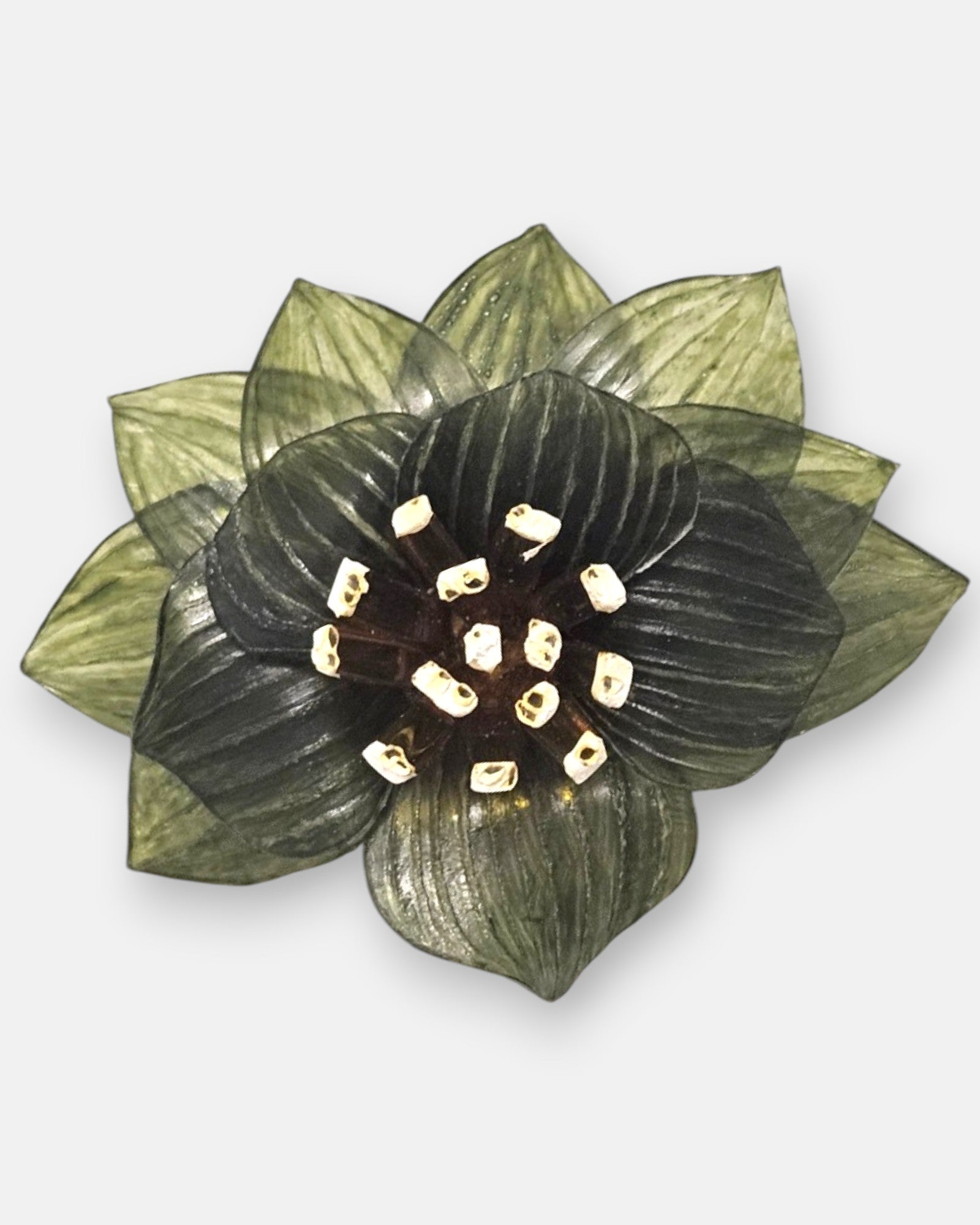 plano macro del broche floral, resaltando las sutiles líneas grabadas en los pétalos verdes y la textura tridimensional de los elementos centrales.