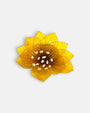 broche con forma de flor de loto de Ciléa Paris sobre fondo claro, apreciando su diseño de pétalos estriados en resina translúcida de color amarillo mostaza.