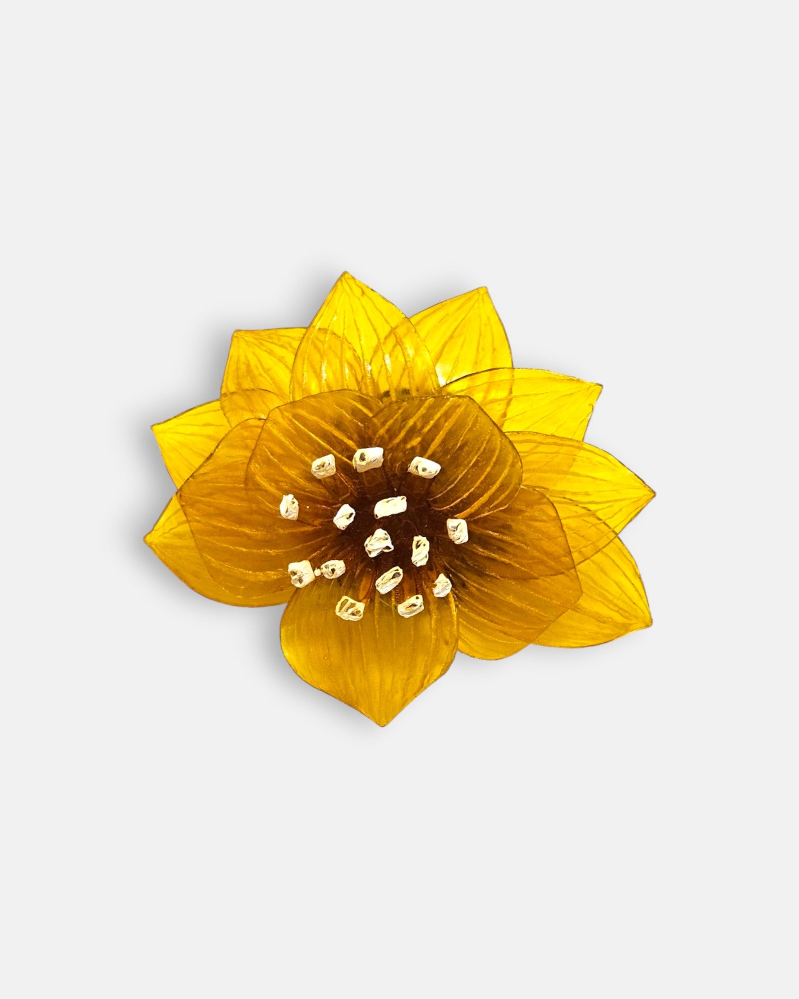 broche con forma de flor de loto de Ciléa Paris sobre fondo claro, apreciando su diseño de pétalos estriados en resina translúcida de color amarillo mostaza.