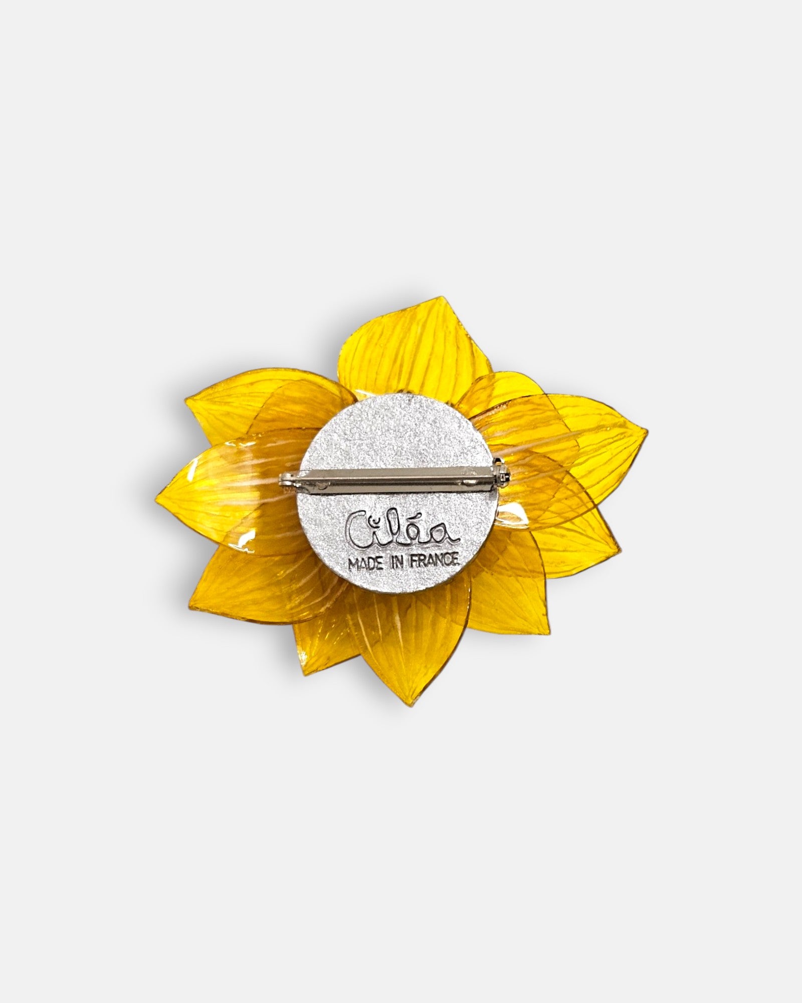 reverso de la pieza artesanal, detallando el pasador metálico de aguja para la sujeción y la firma oficial grabada "Ciléa Made in France".