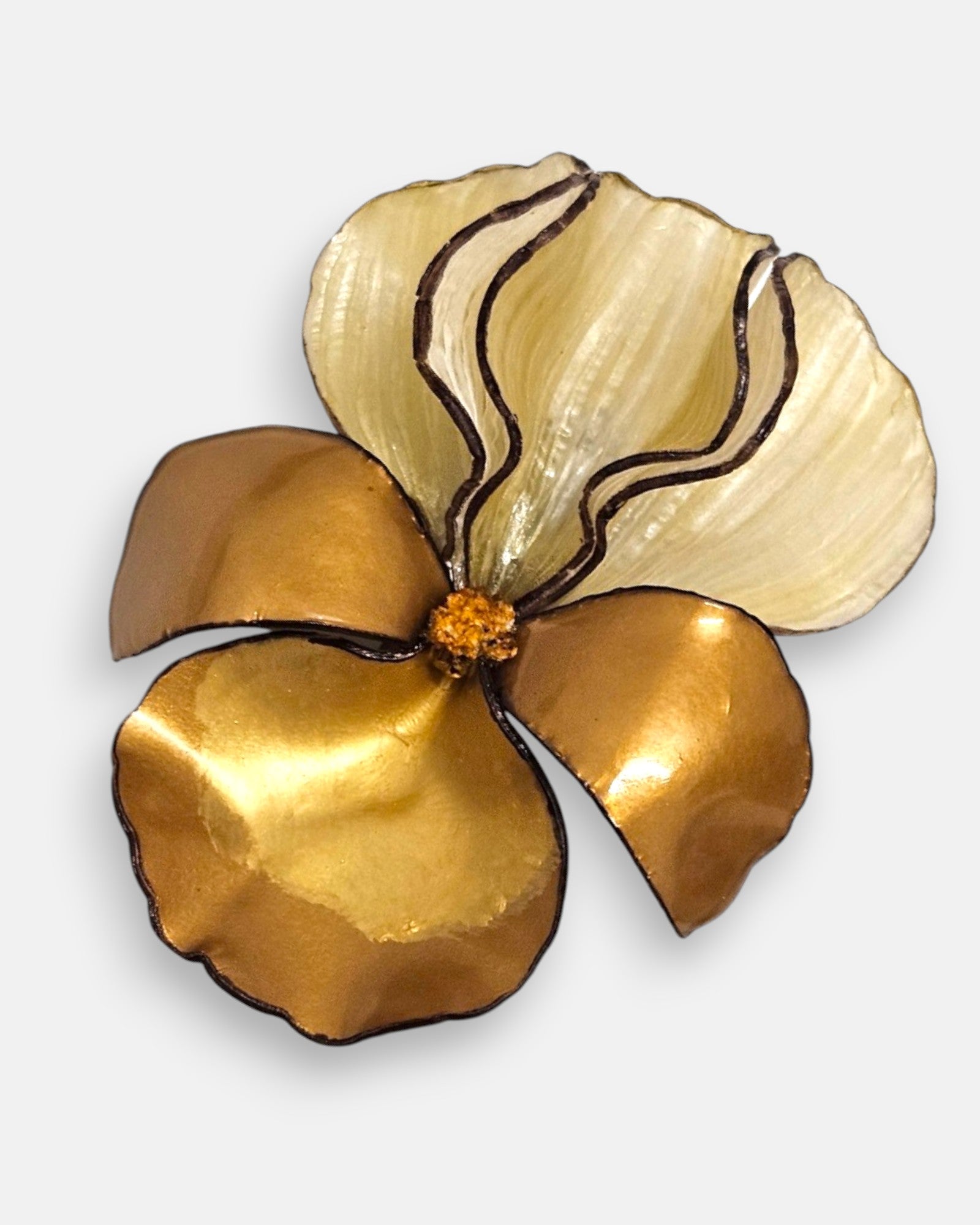primer plano macro en ángulo del broche floral, permitiendo apreciar las líneas grabadas de los pétalos de resina translúcida y los reflejos bronceados de la base.