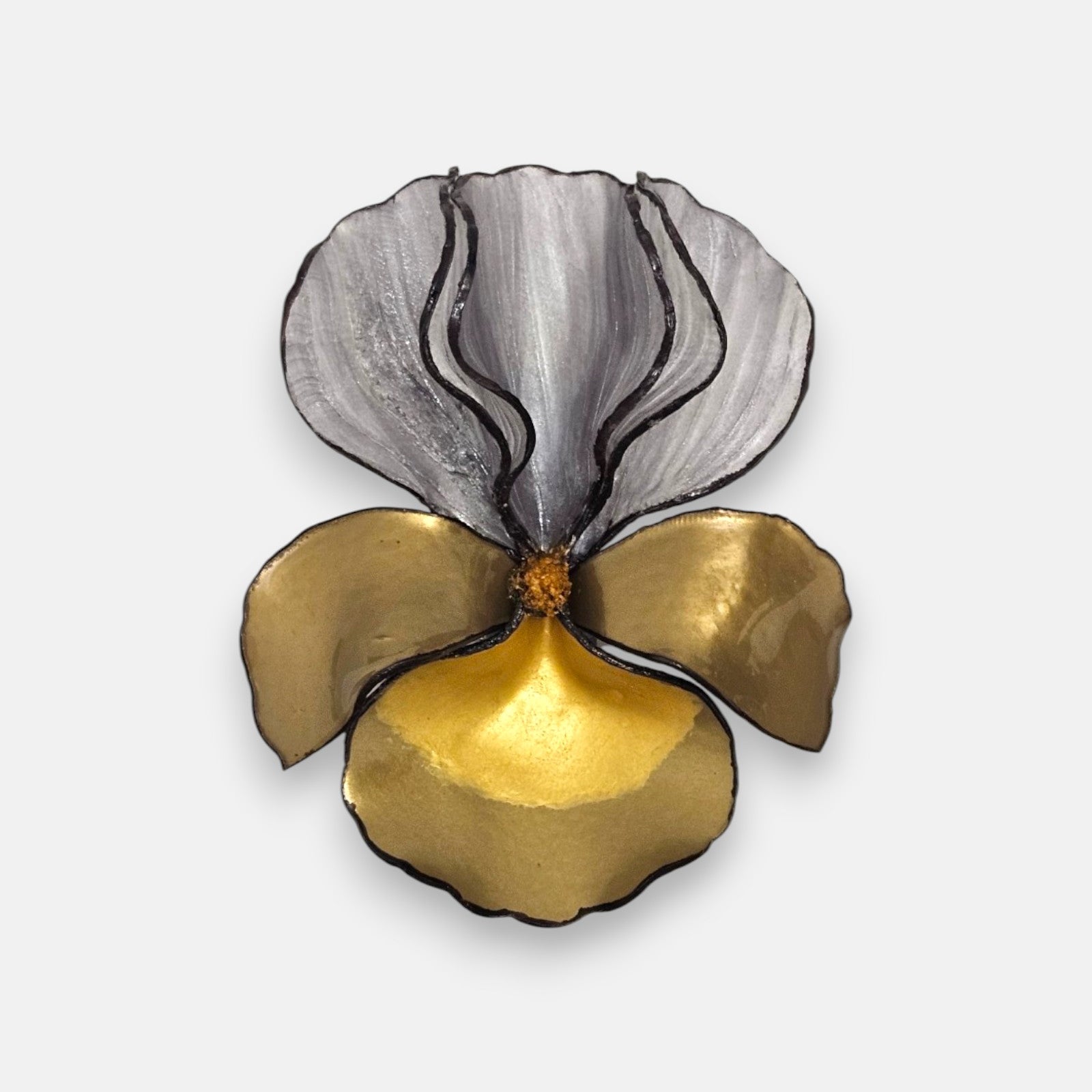 broche con forma de flor de iris sobre fondo neutro, resaltando sus pétalos superiores plateados y la base metálica en tonos oro.