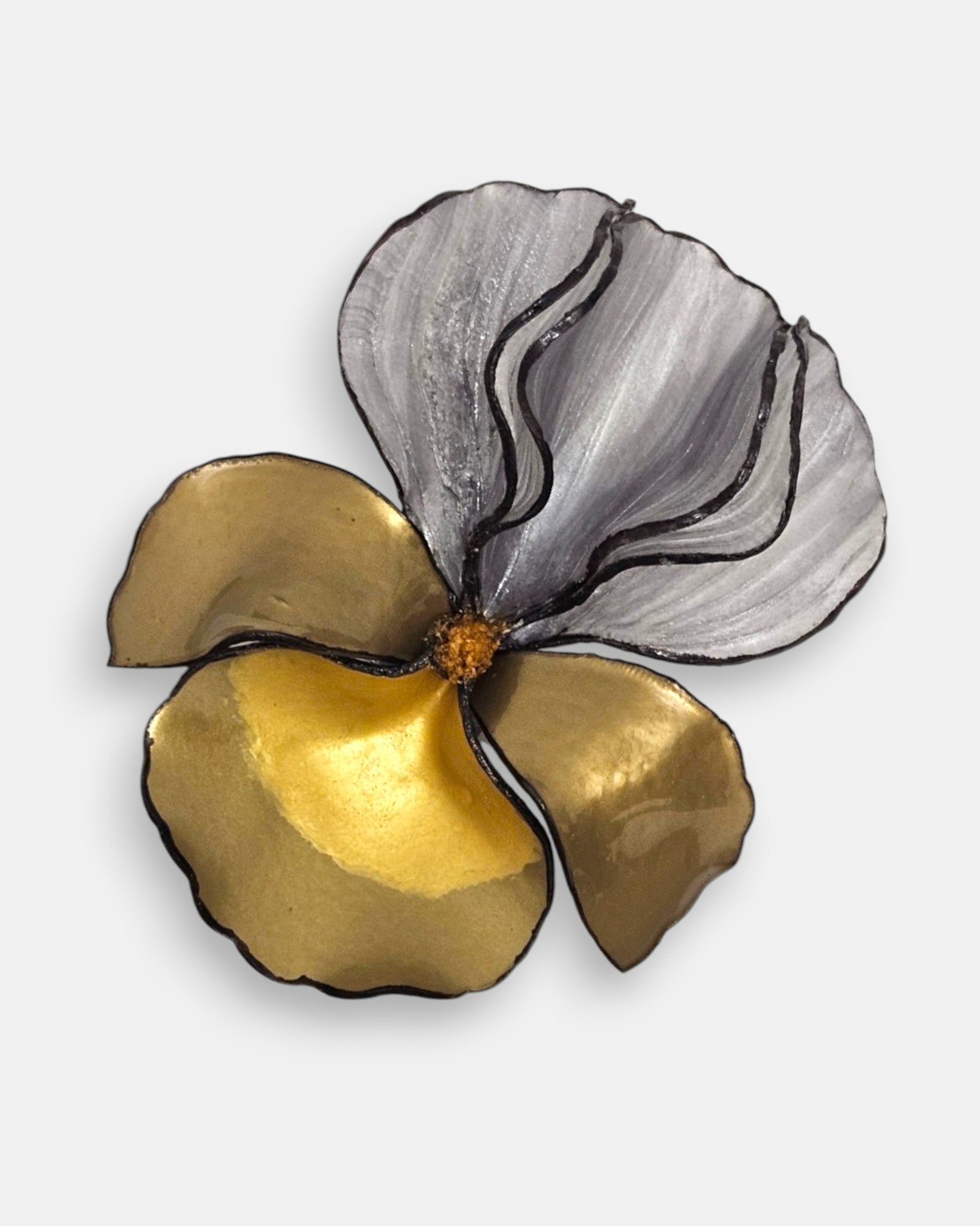 primer plano macro en ángulo del broche floral, permitiendo apreciar las finas estrías de los pétalos de resina gris y los reflejos dorados de la base.