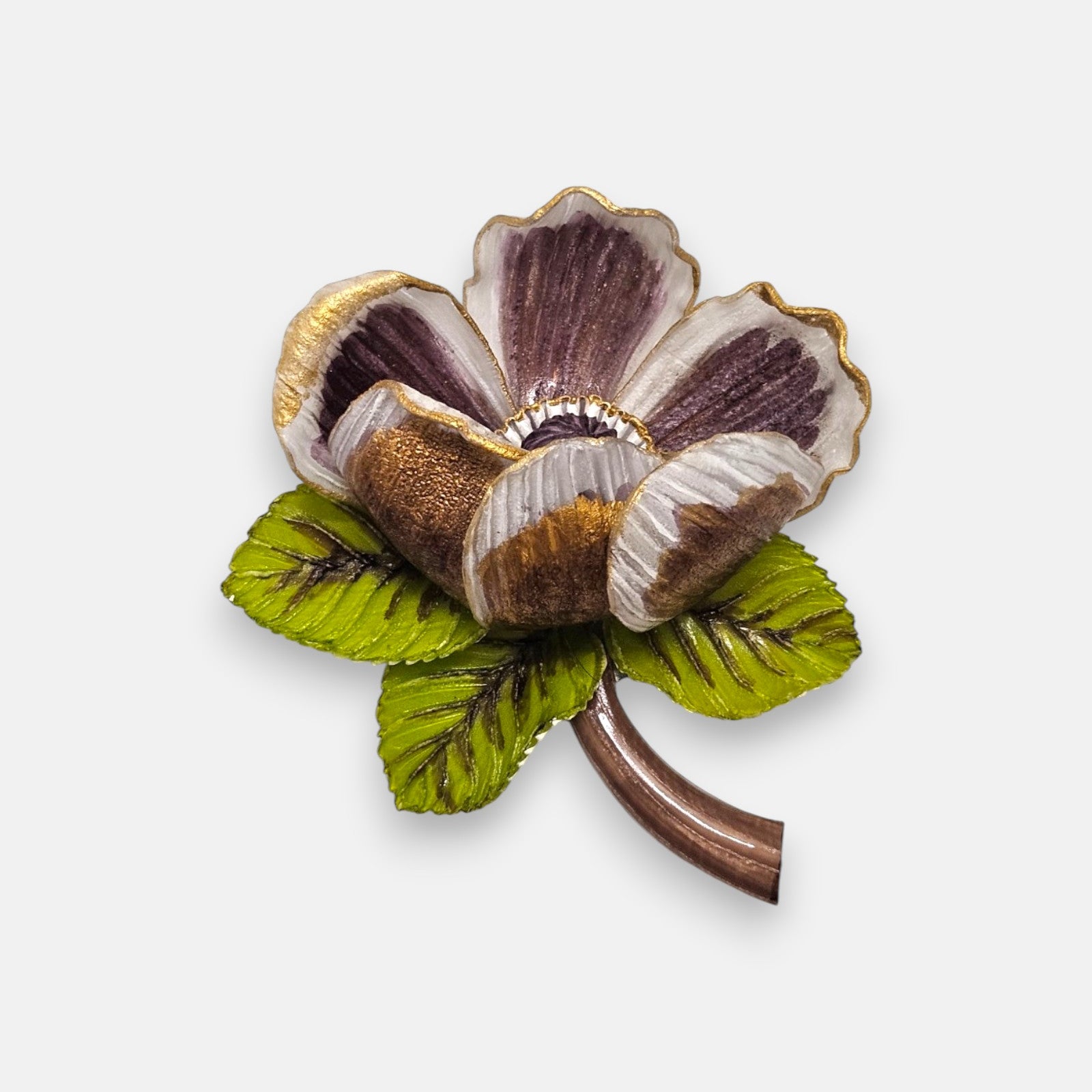 broche de flor silvestre de Ciléa Paris sobre fondo claro, apreciando sus pétalos estriados violetas con bordes dorados, sus hojas verdes y su tallo marrón.