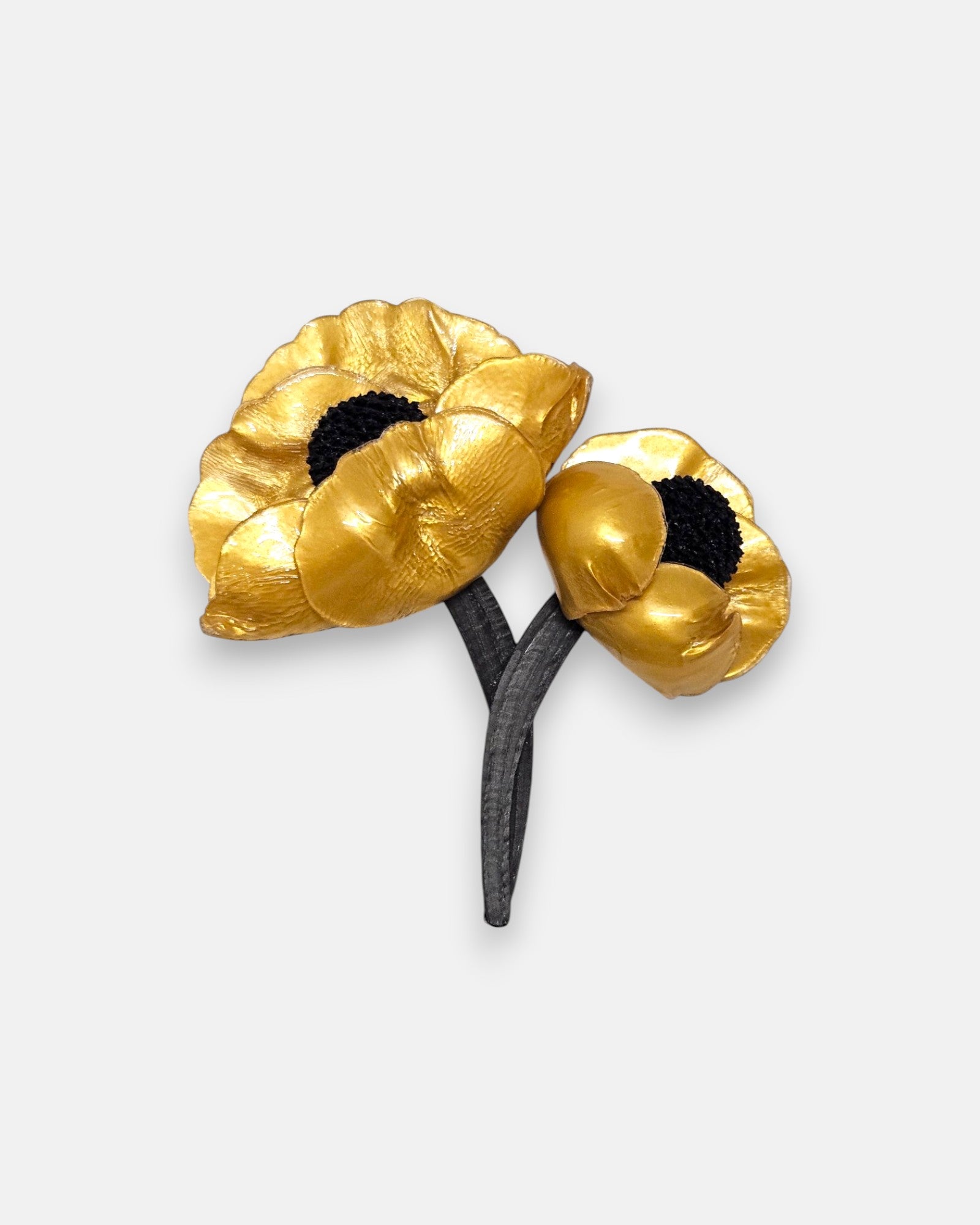 broche de doble flor de Ciléa Paris sobre fondo claro, apreciando el acabado satinado de sus pétalos dorados con centros negros y tallos entrelazados.
