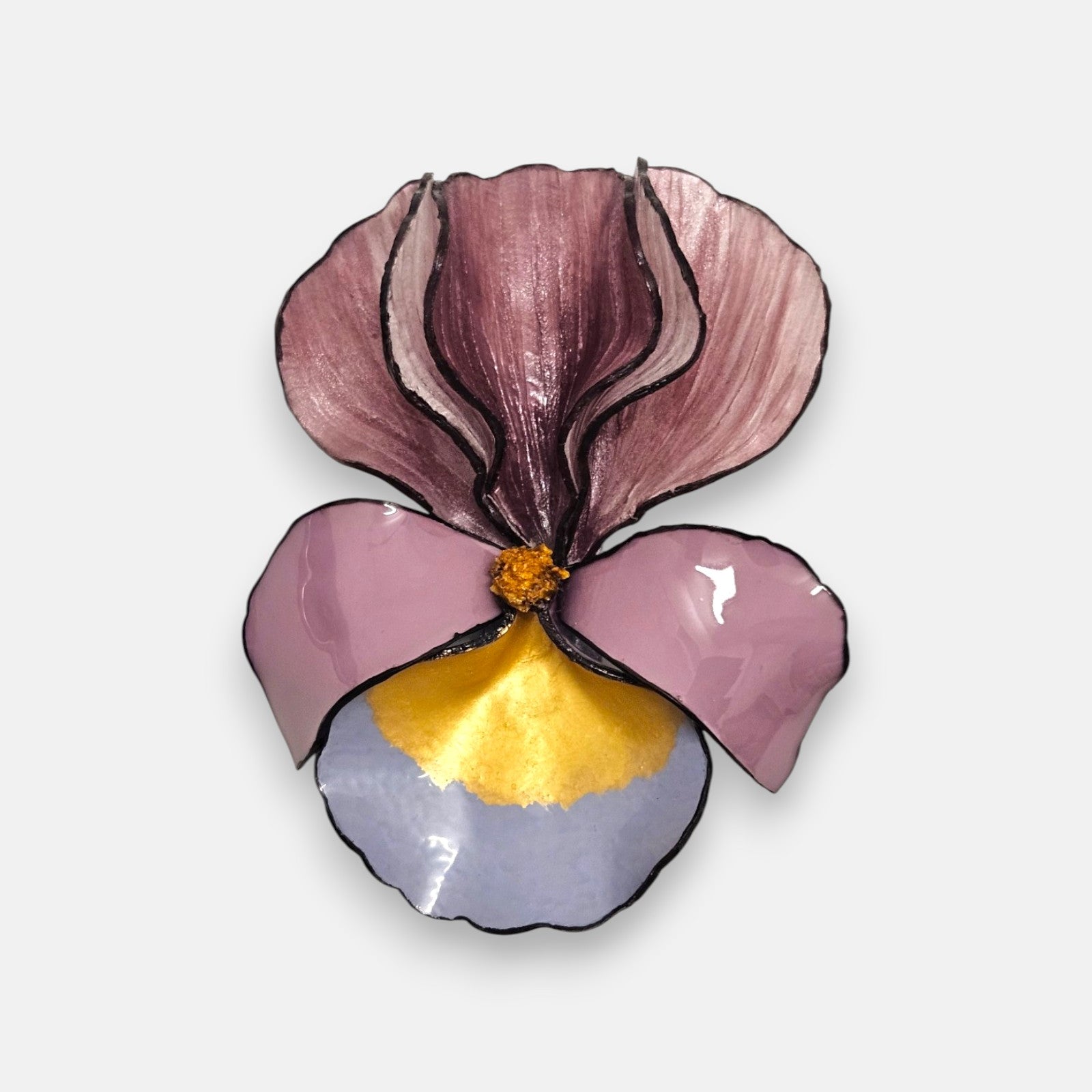 broche con forma de flor de iris sobre fondo neutro, destacando sus pétalos superiores en color malva y su base en tonos rosa, azul lavanda y oro satinado.