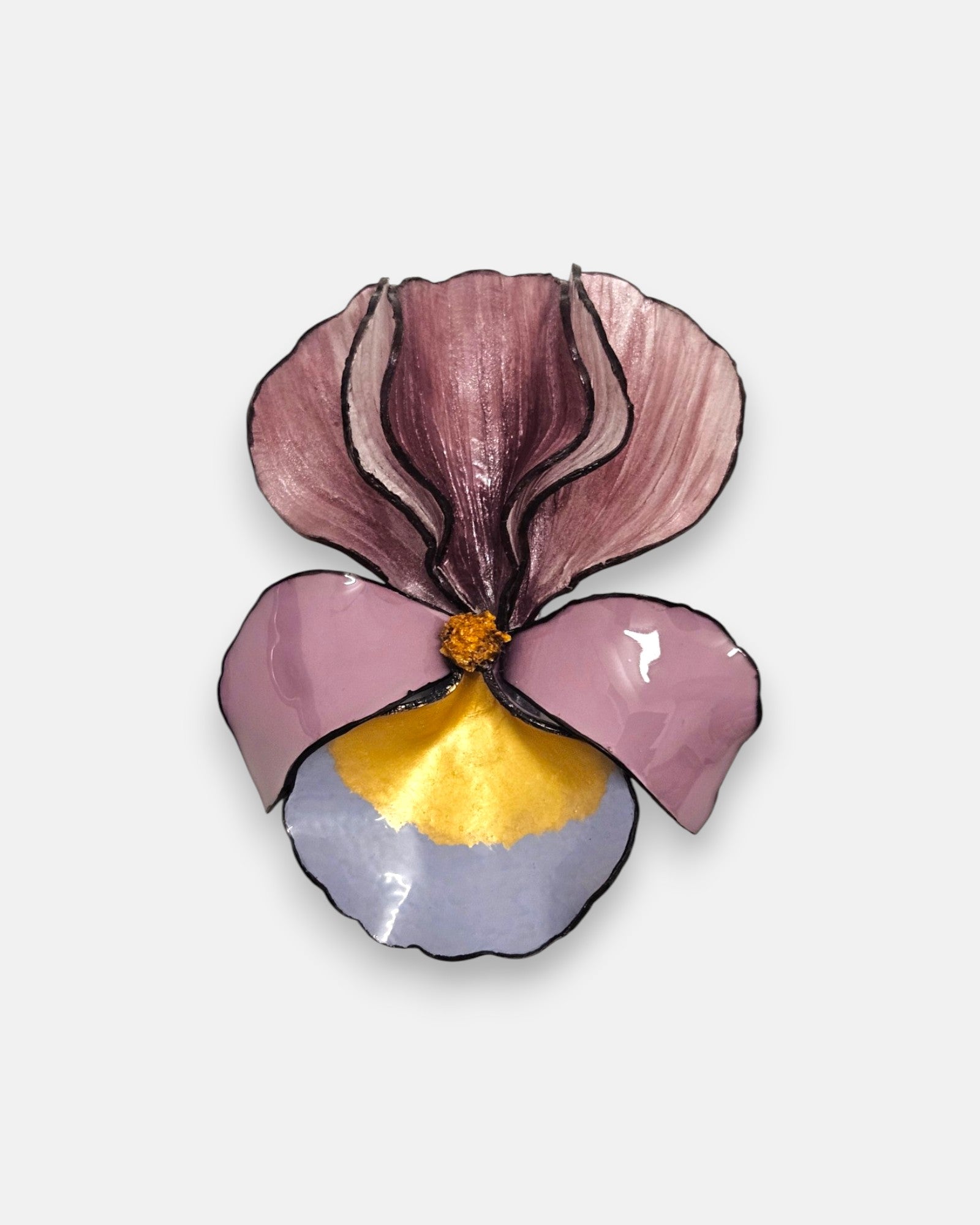 broche con forma de flor de iris sobre fondo neutro, destacando sus pétalos superiores en color malva y su base en tonos rosa, azul lavanda y oro satinado.