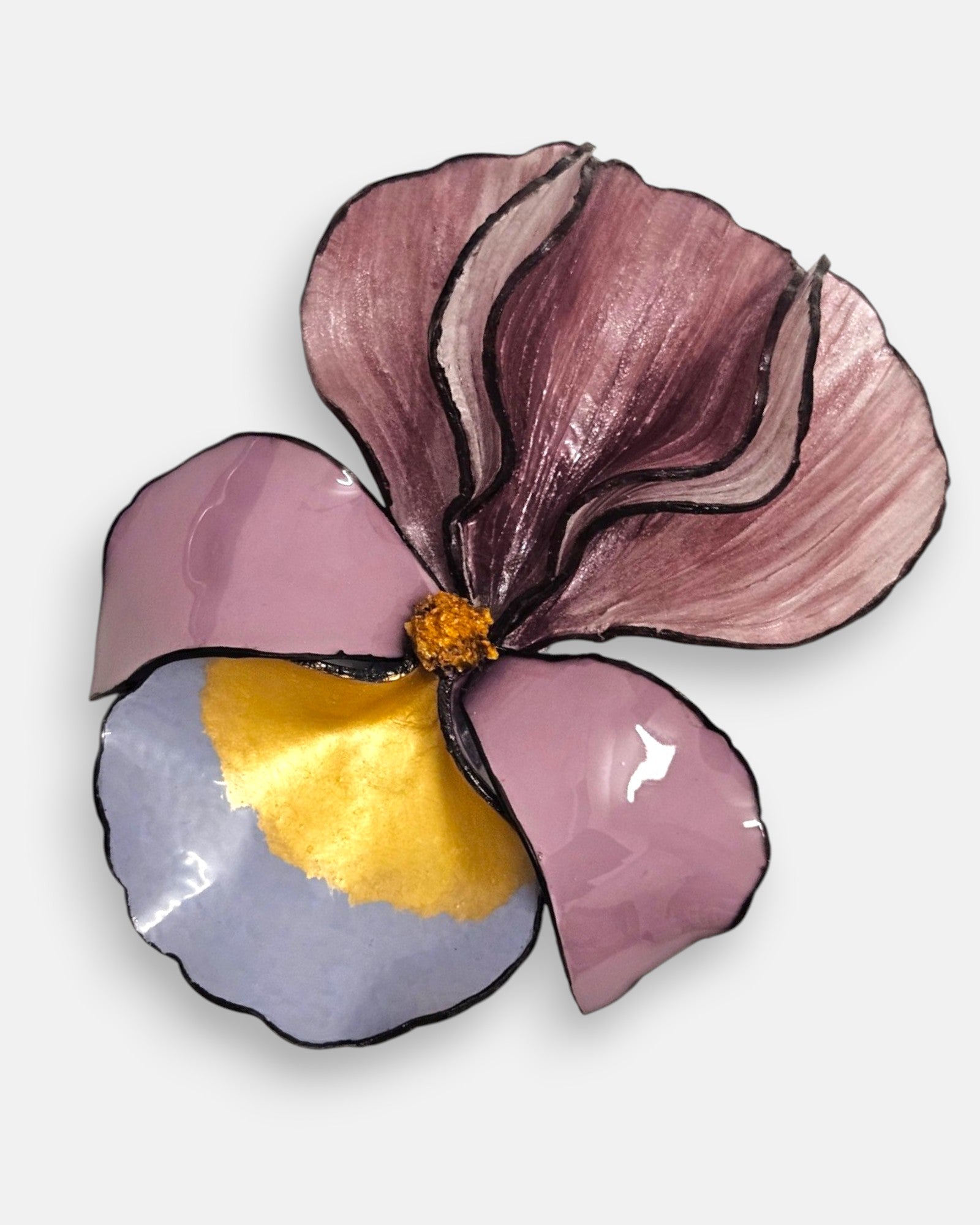 primer plano macro en ángulo del broche floral, permitiendo apreciar el brillo esmaltado de los pétalos de resina inferiores y el relieve estriado de la sección superior.