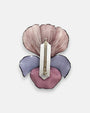 modelo luciendo el broche maxi de iris malva prendido en la solapa de una americana de sastre gris oscuro, apreciando su escala maximalista y elegante.