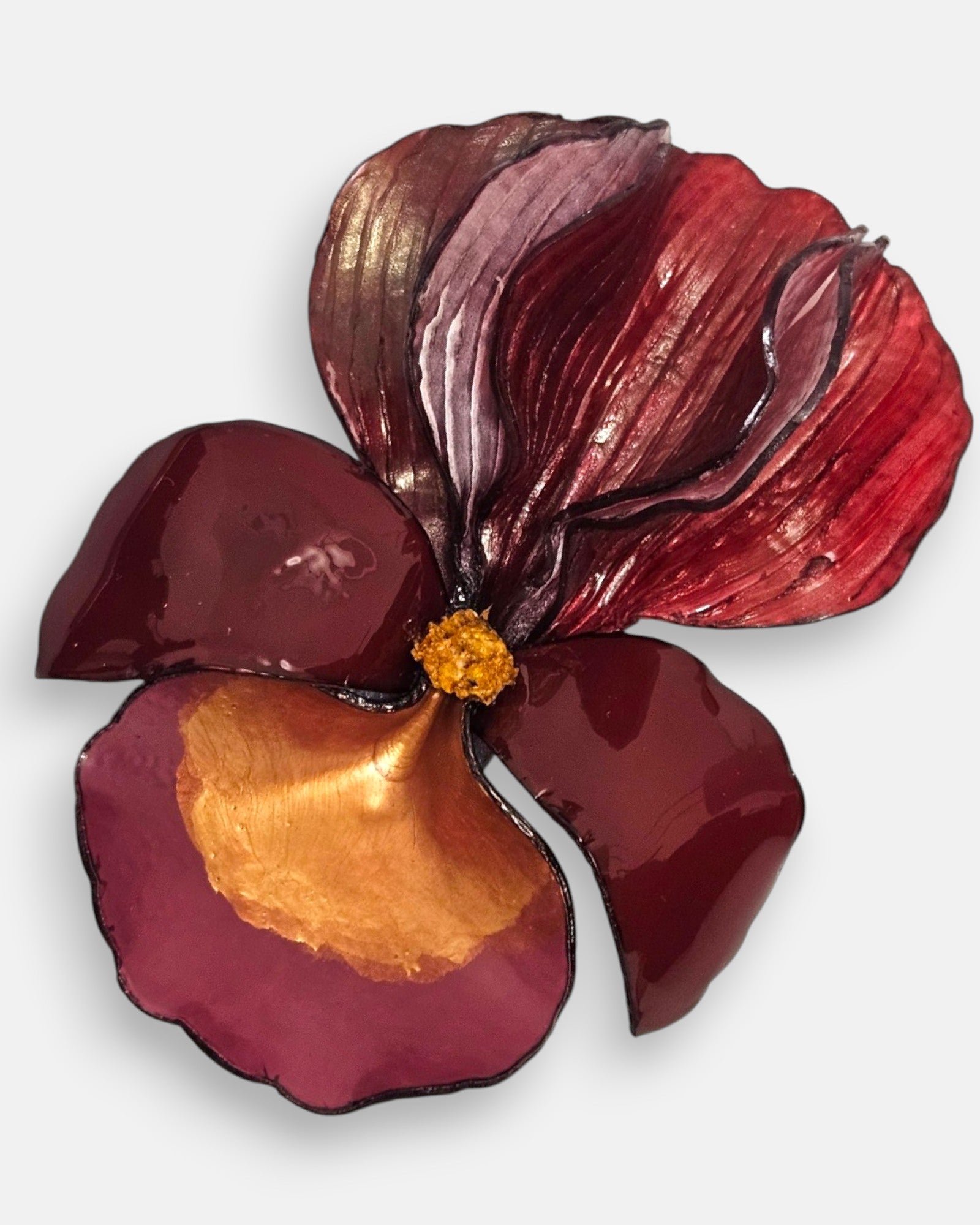 primer plano macro en ángulo del broche floral, permitiendo apreciar el brillo esmaltado de los pétalos de resina inferiores y el relieve estriado de la sección superior.