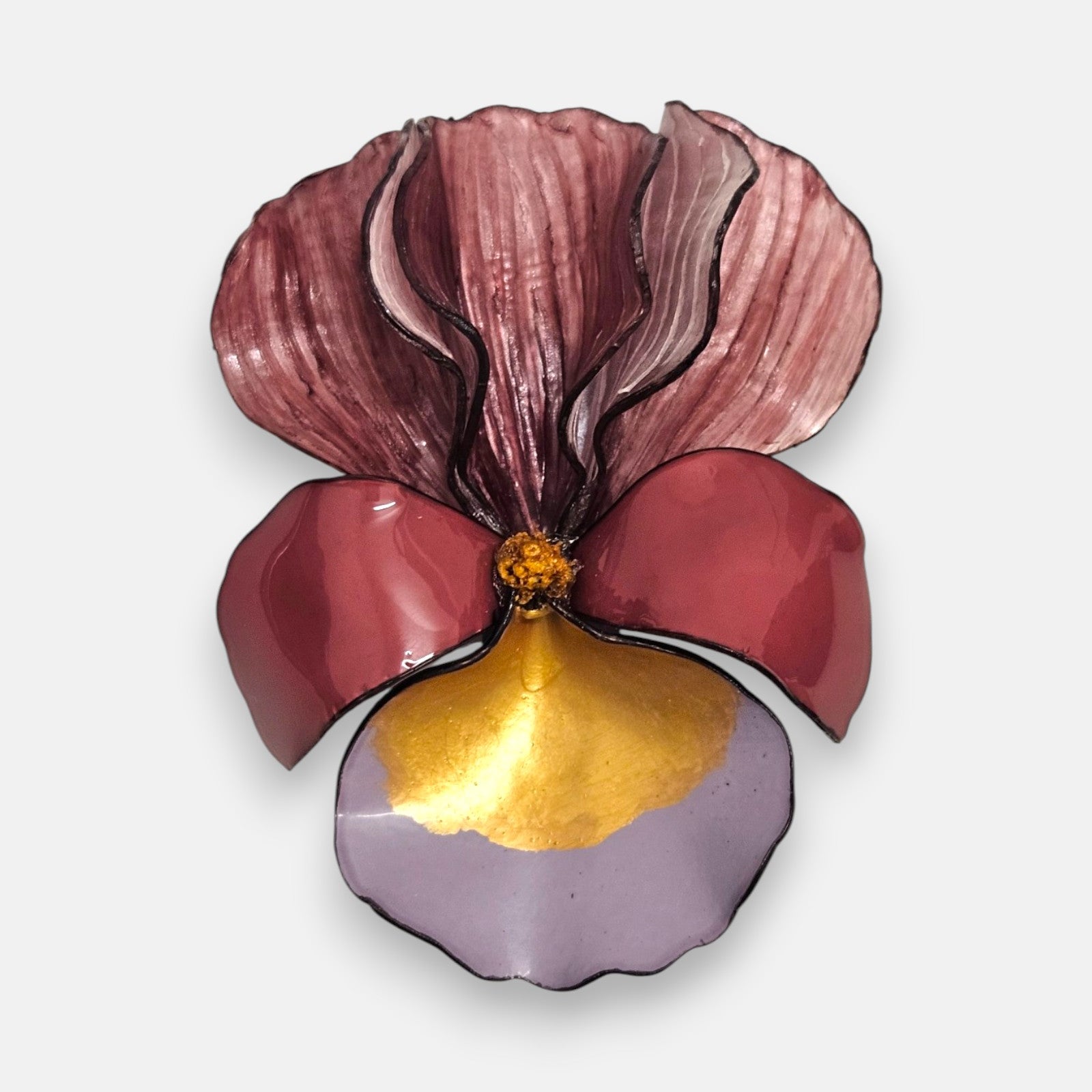 broche con forma de flor de iris sobre fondo neutro, destacando sus pétalos superiores en color burdeos difuminado y su base en tonos vino, azul lavanda y oro satinado.