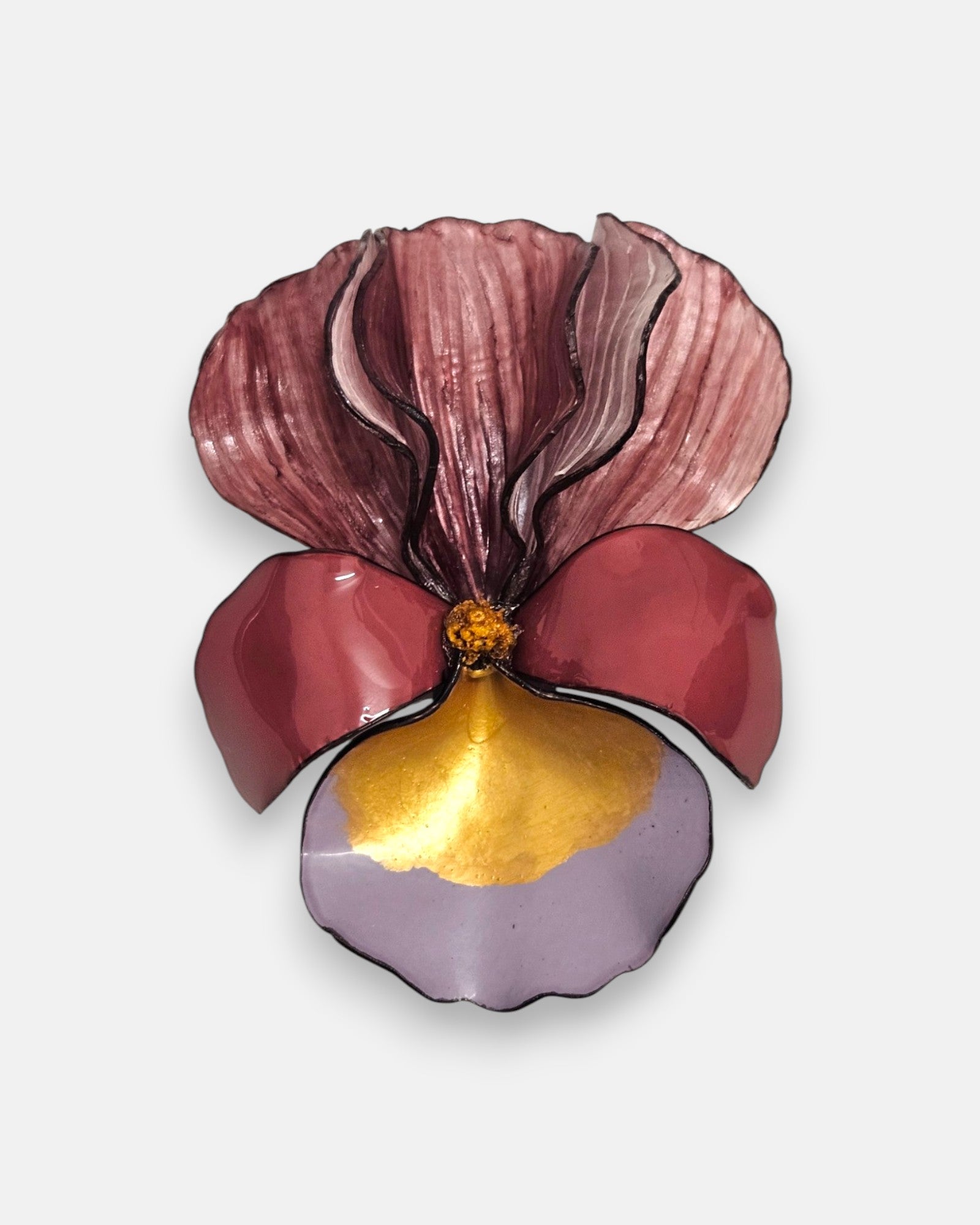 broche con forma de flor de iris sobre fondo neutro, destacando sus pétalos superiores en color burdeos difuminado y su base en tonos vino, azul lavanda y oro satinado.