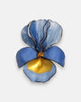 broche con forma de flor de iris sobre fondo neutro, destacando sus pétalos superiores en azul degradado y su base en tonos azul cerúleo y oro satinado.