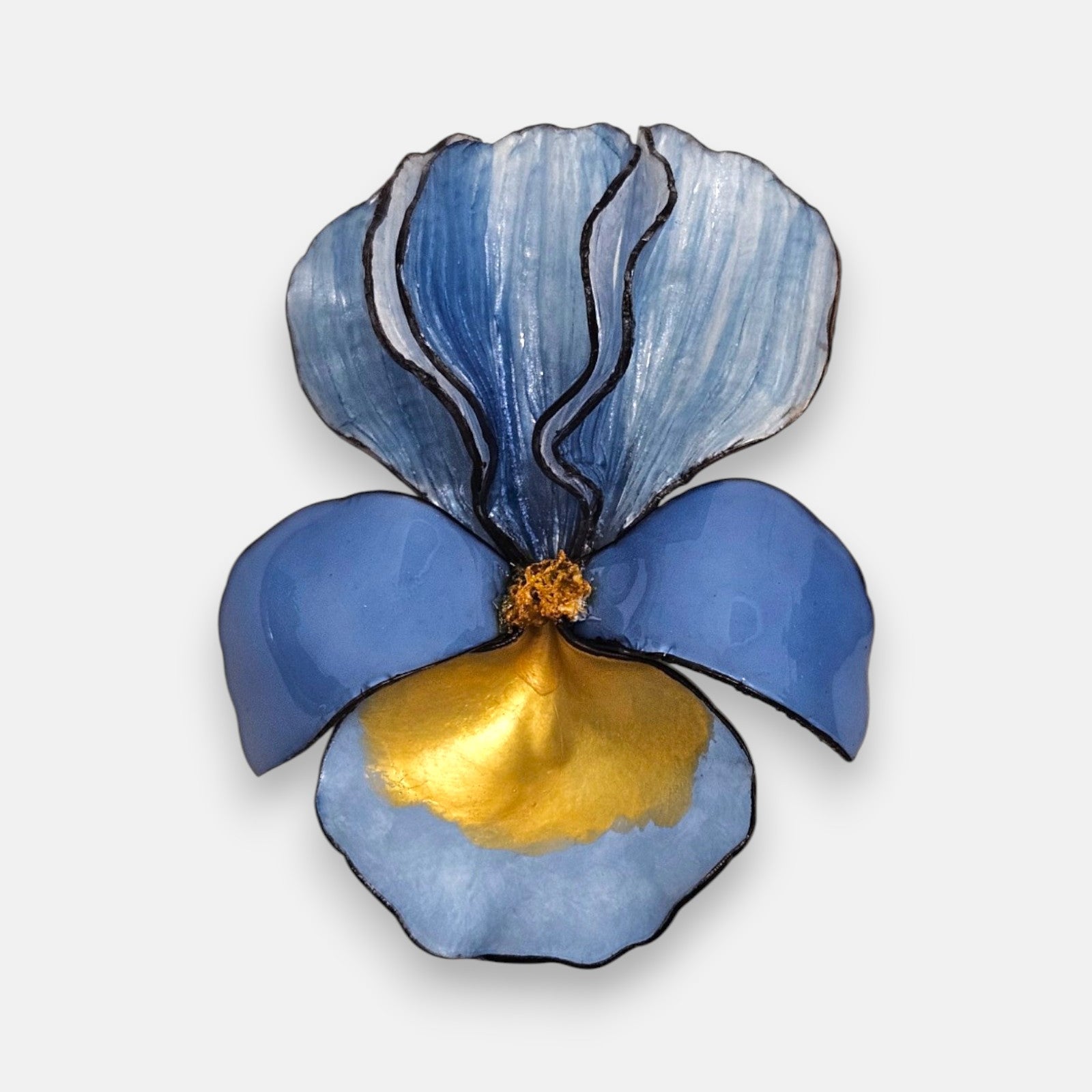 broche con forma de flor de iris sobre fondo neutro, destacando sus pétalos superiores en azul degradado y su base en tonos azul cerúleo y oro satinado.