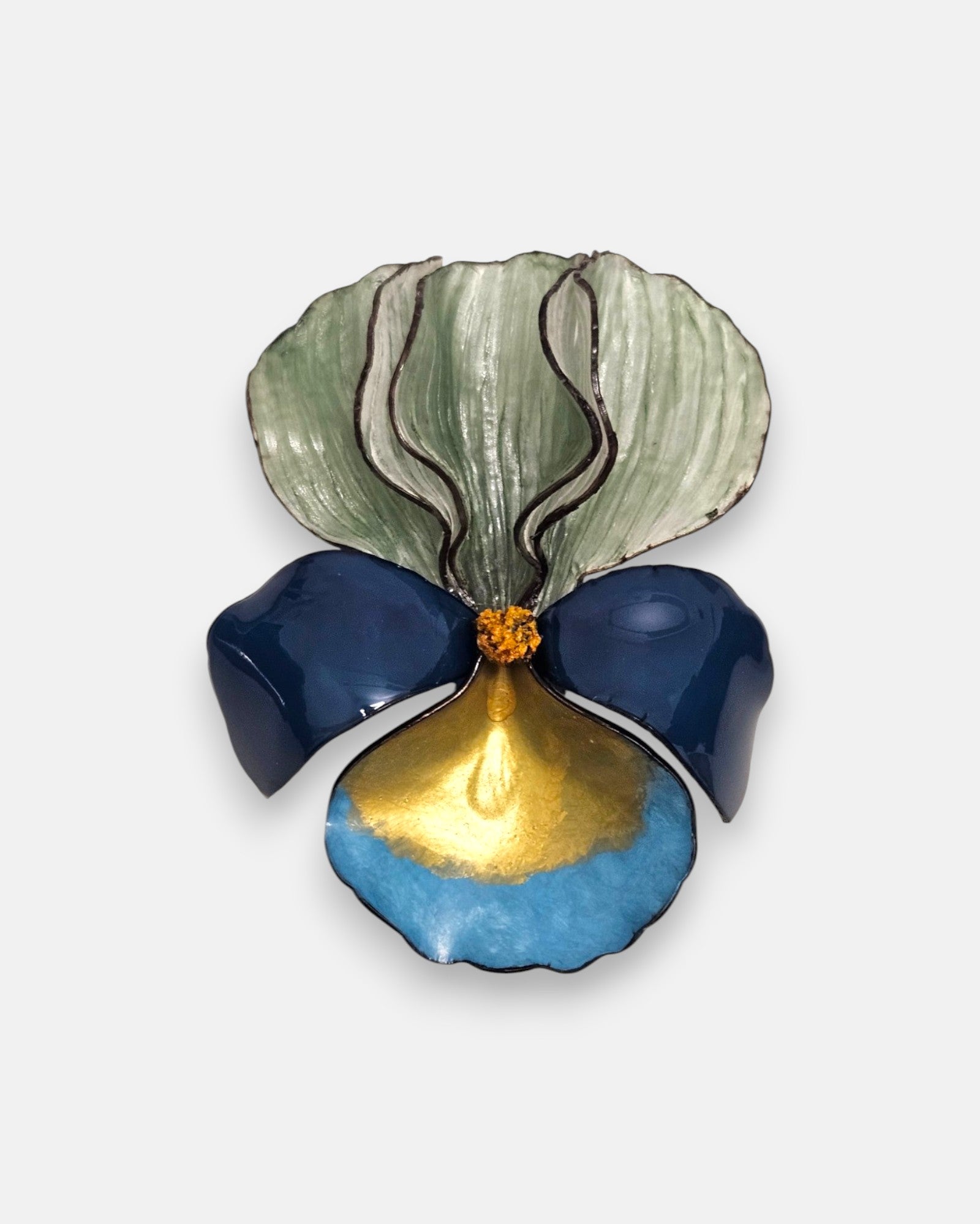 broche con forma de flor de iris sobre fondo neutro, destacando sus pétalos superiores en verde menta degradado y su base en tonos azul marino, turquesa y oro satinado.