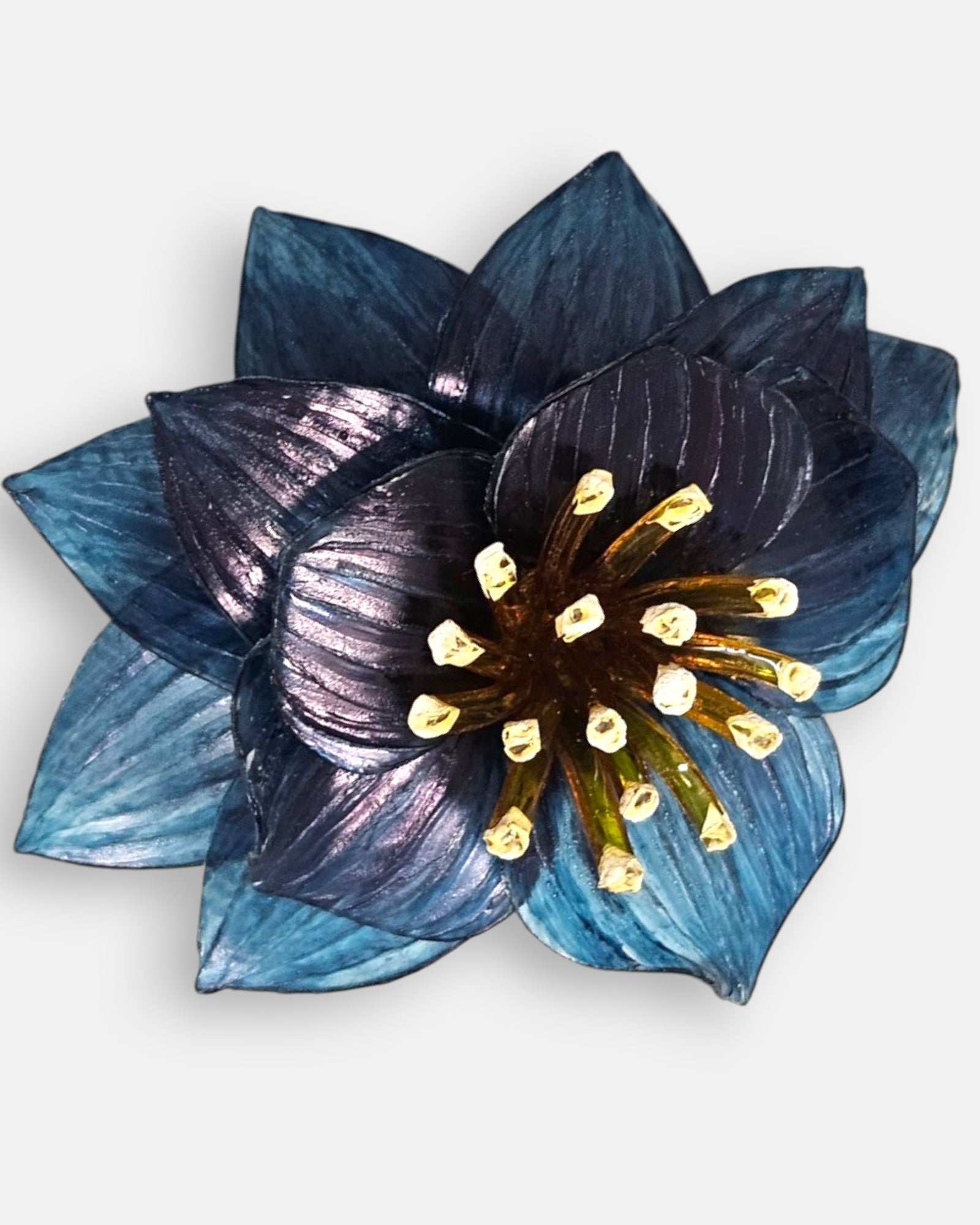 plano macro del broche floral, resaltando las sutiles líneas grabadas en los pétalos azules y la textura tridimensional de los elementos centrales.