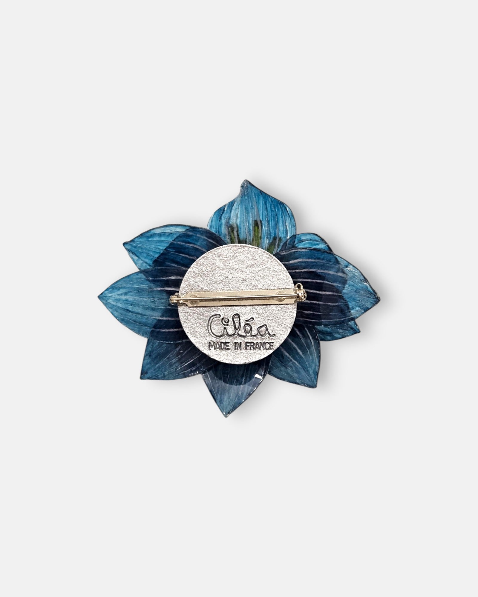 reverso de la pieza artesanal, detallando la base metálica con el pasador de aguja para la sujeción y el sello grabado de la marca "Ciléa Made in France".