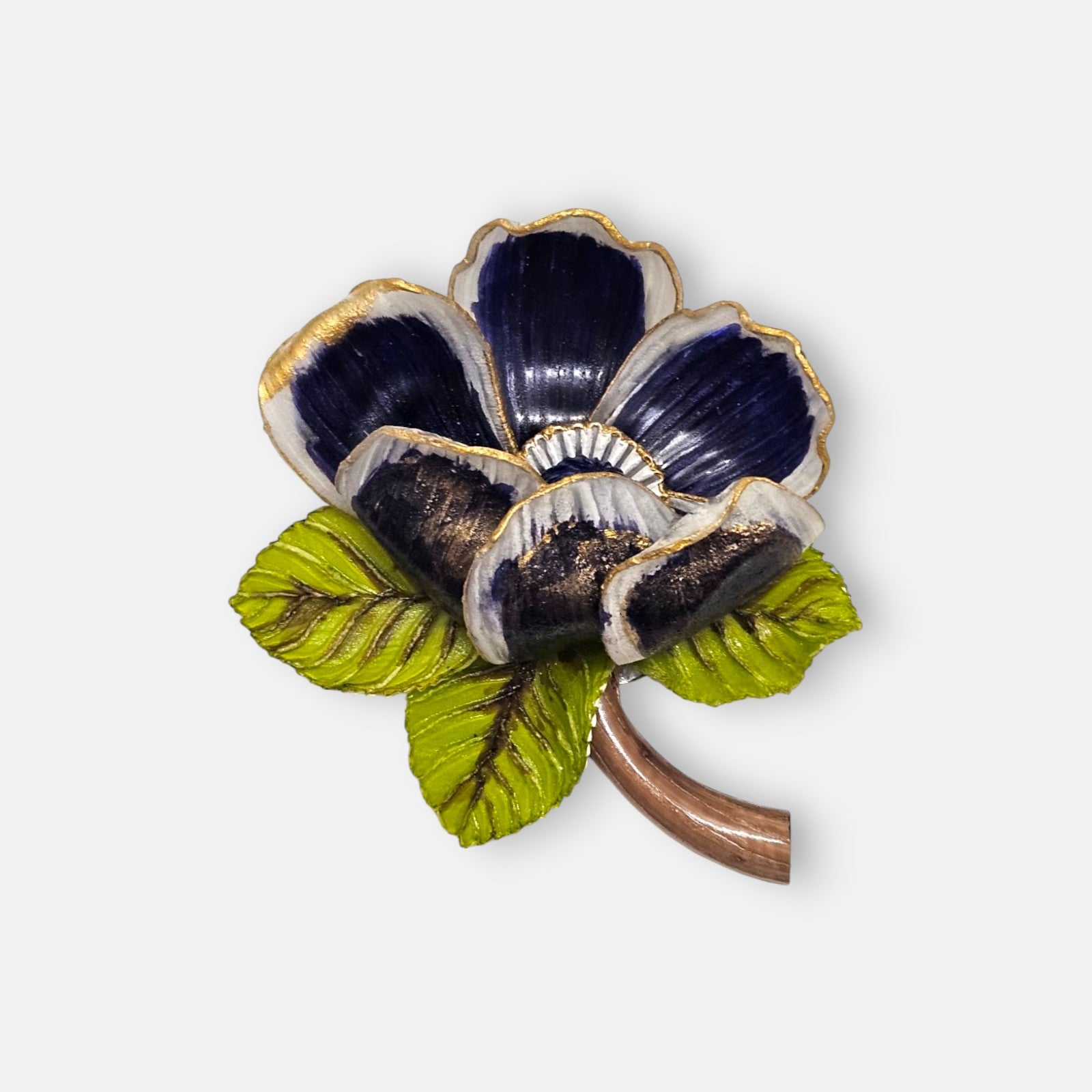 broche de flor silvestre de Ciléa Paris sobre fondo claro, apreciando sus pétalos estriados azul noche con bordes dorados, sus hojas verdes y su tallo marrón.