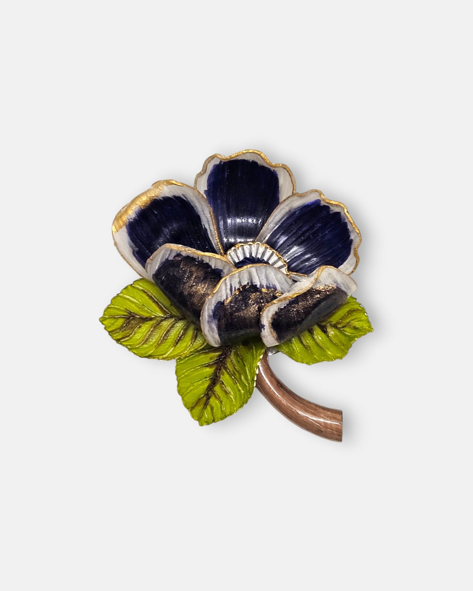 broche de flor silvestre de Ciléa Paris sobre fondo claro, apreciando sus pétalos estriados azul noche con bordes dorados, sus hojas verdes y su tallo marrón.