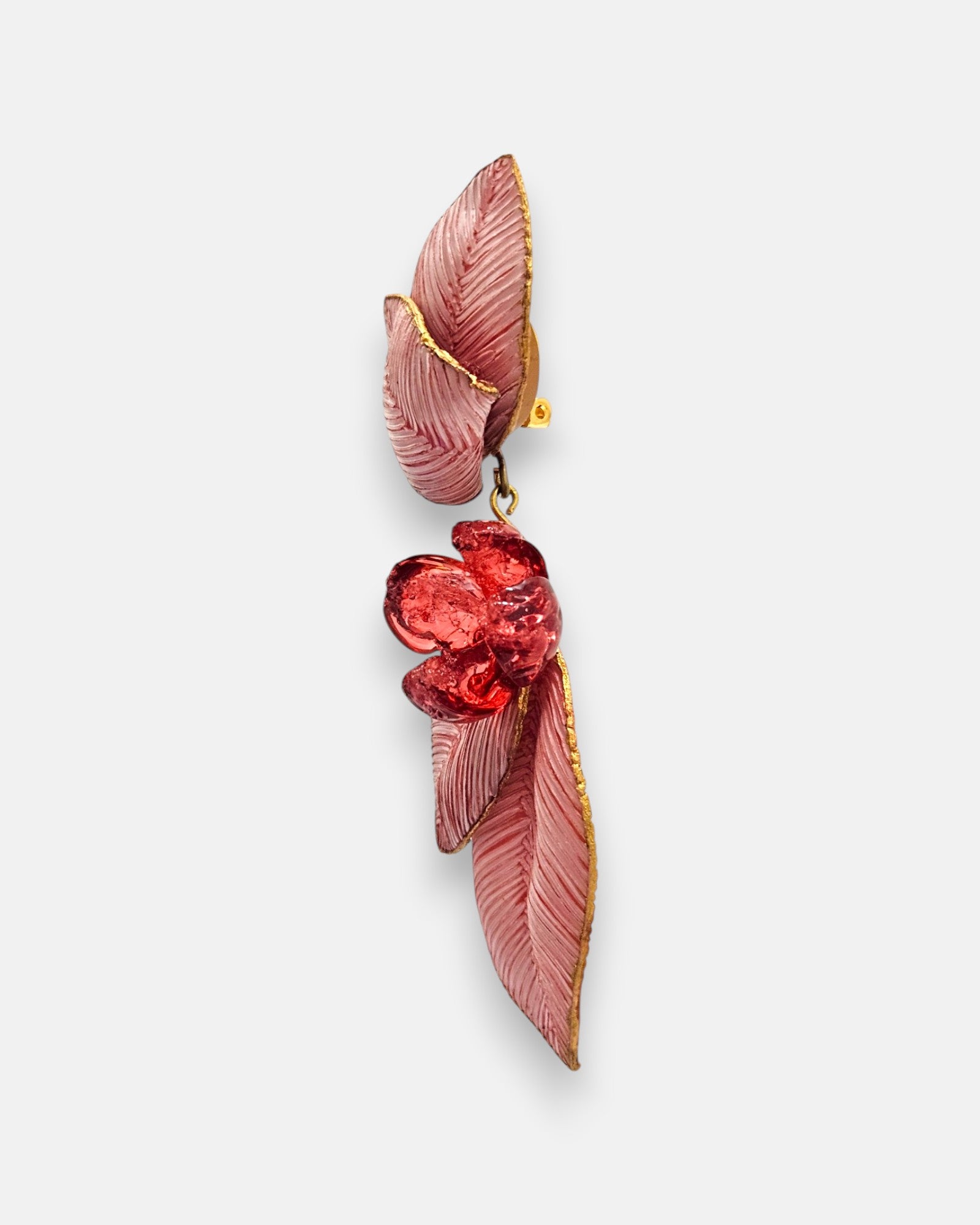perspectiva de perfil de la pieza de autor, dejando ver la superposición tridimensional de las hojas de resina, el relieve de la flor central roja y el mecanismo de pinza trasero.