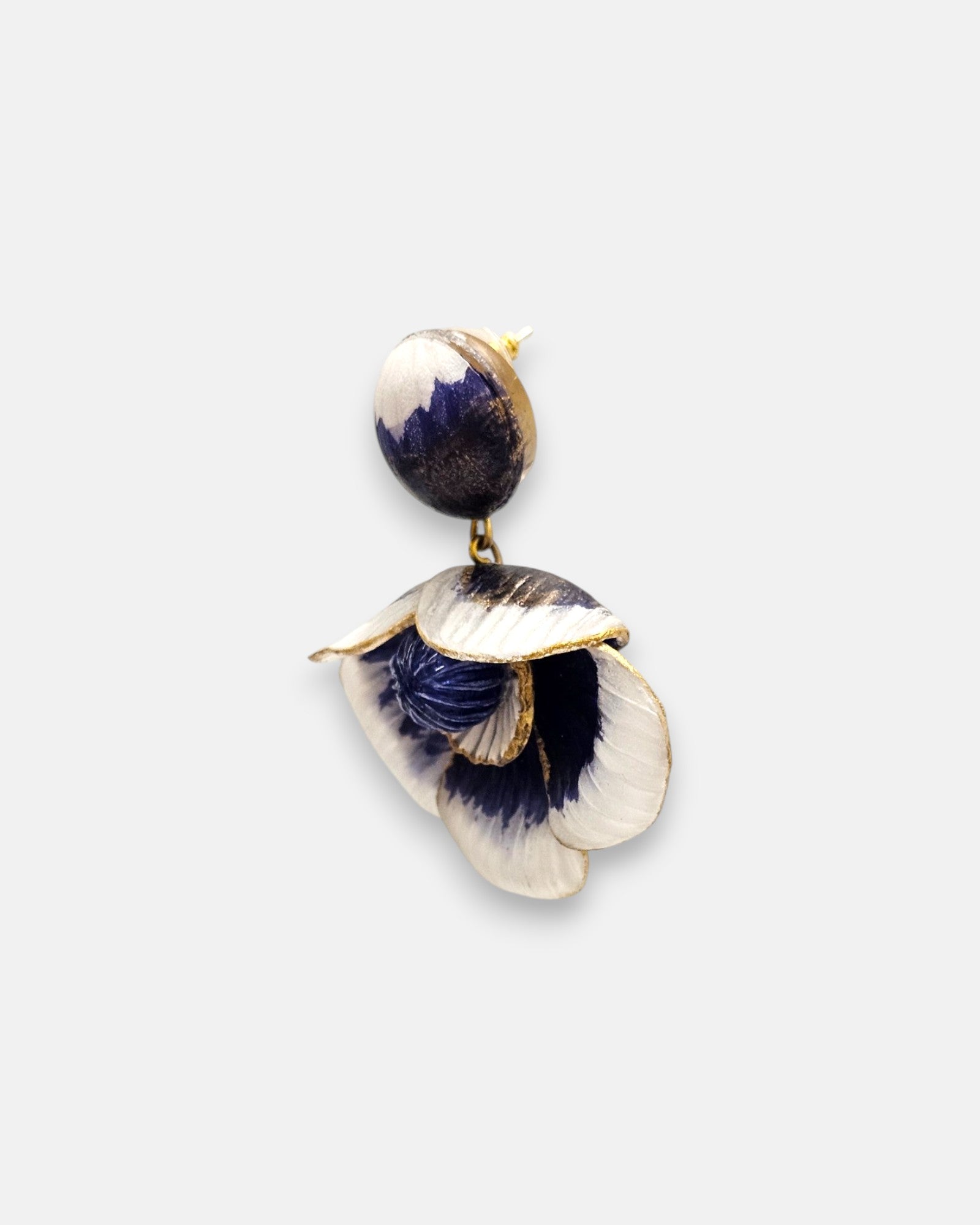 modelo luciendo el pendiente colgante de flor azul y blanca, apreciando su escala maximalista, su relieve tridimensional y cómo adorna el rostro con sofisticación.