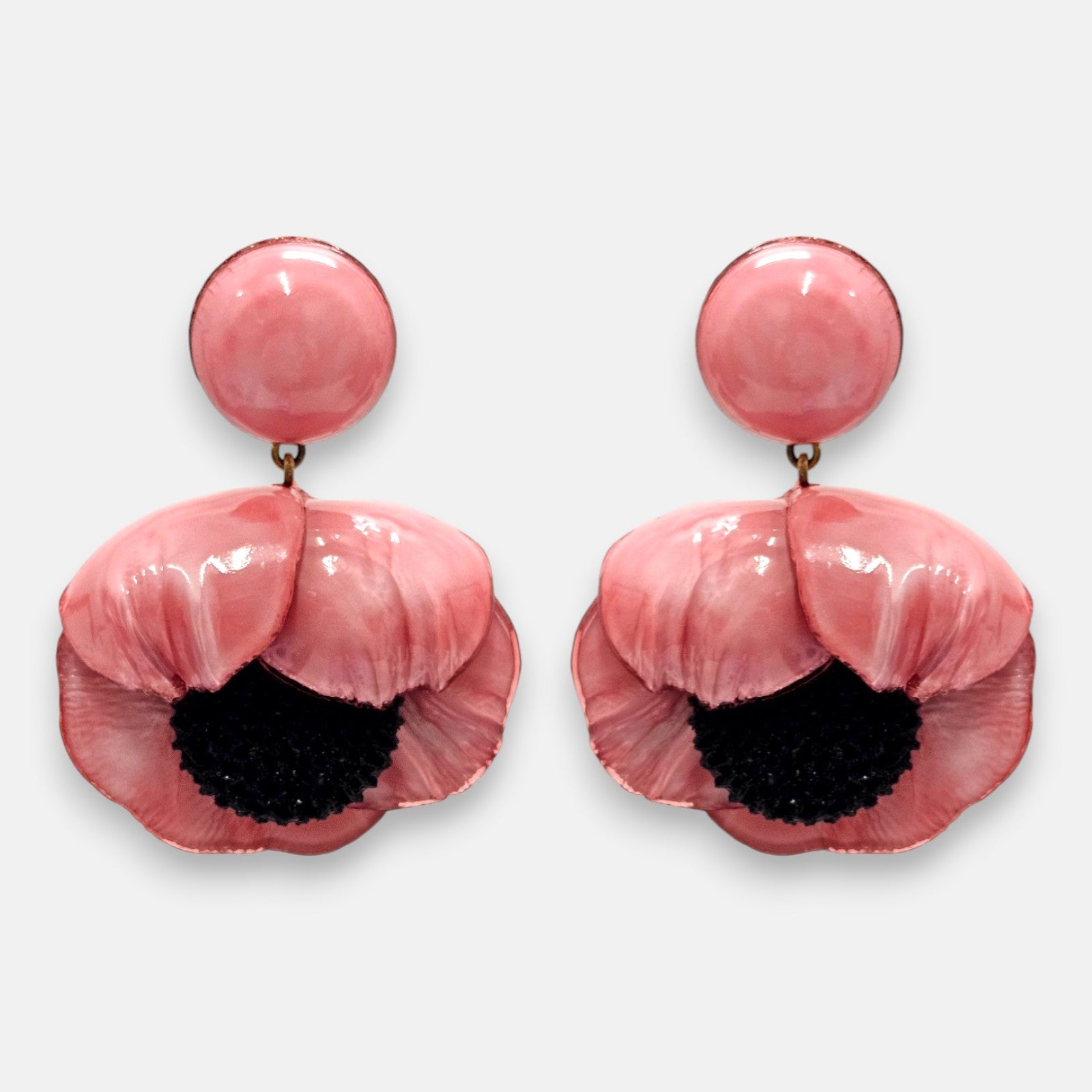 par de pendientes con forma de flor de amapola de Ciléa Paris sobre fondo claro, detallando su botón superior redondo y sus pétalos volumétricos rosa chicle con centro negro.