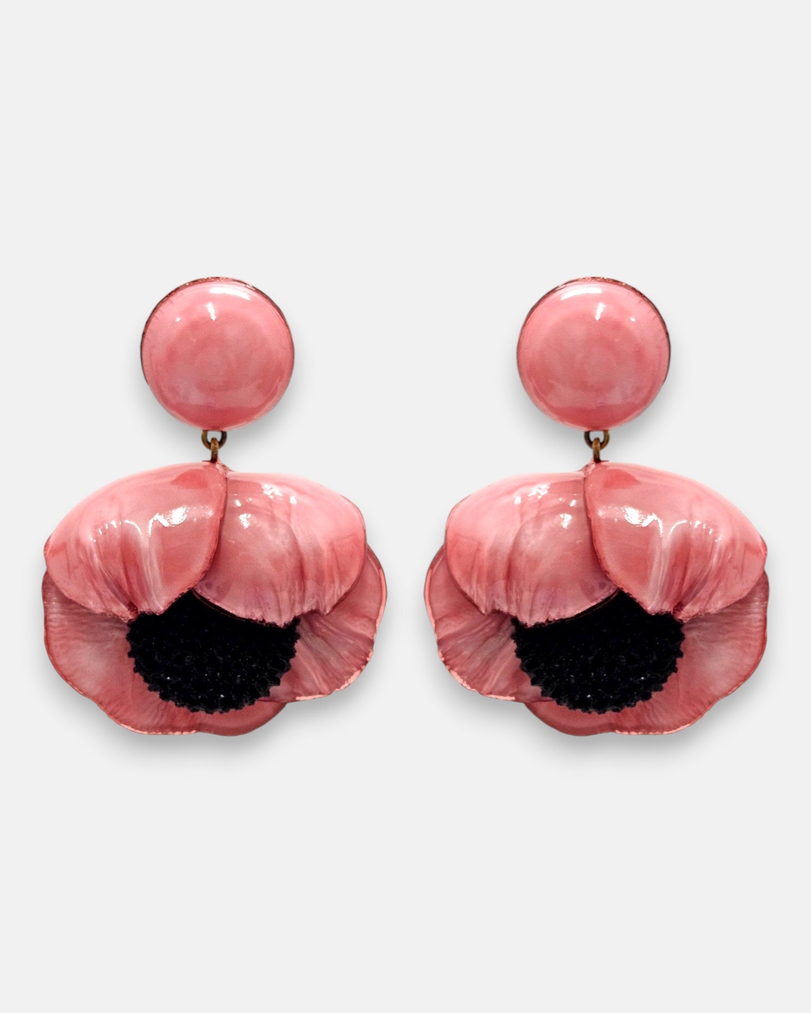 par de pendientes con forma de flor de amapola de Ciléa Paris sobre fondo claro, detallando su botón superior redondo y sus pétalos volumétricos rosa chicle con centro negro.