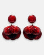 par de pendientes con forma de flor de amapola de Ciléa Paris sobre fondo claro, detallando su botón superior redondo y sus pétalos volumétricos en rojo carmín con centro negro.
