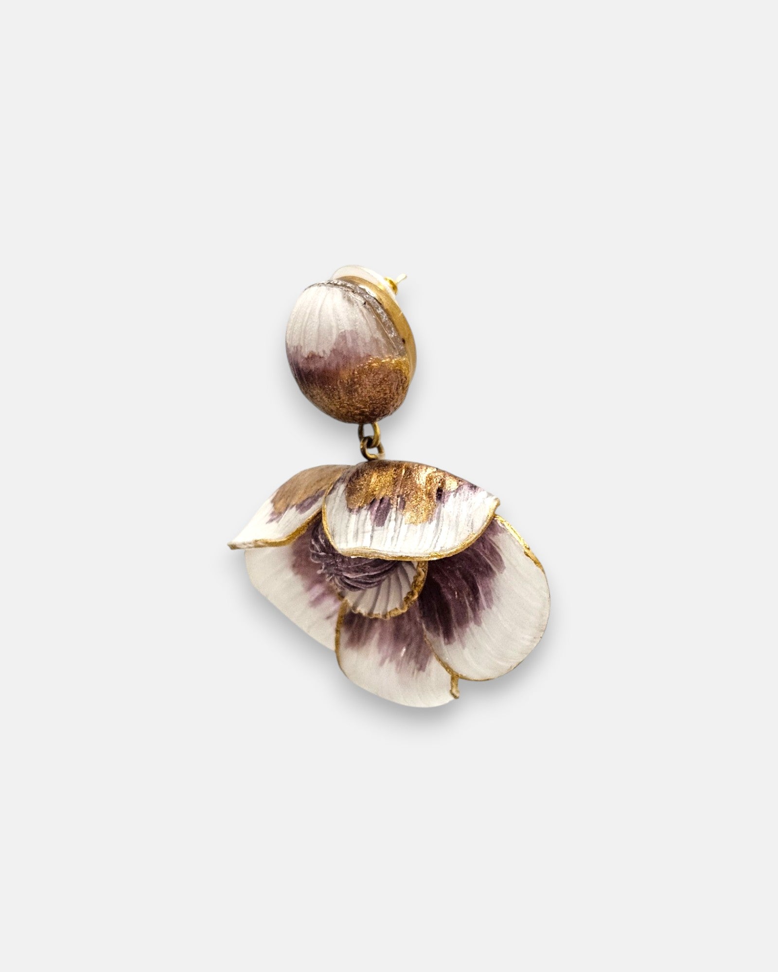 modelo luciendo el pendiente colgante de flor malva y blanca, apreciando su escala maximalista, su relieve tridimensional y cómo adorna el rostro con sofisticación.