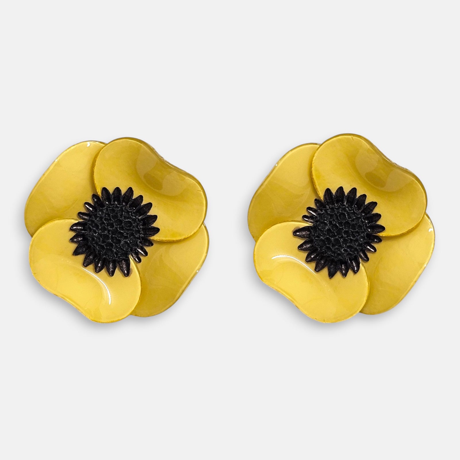 par de pendientes de botón con forma de flor de amapola de Ciléa Paris sobre fondo claro, detallando sus pétalos volumétricos en amarillo mostaza brillante con un gran centro negro.