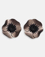 par de pendientes de clip con forma de flor de amapola de Ciléa Paris, detallando sus pétalos de resina metalizada en tono bronce y su gran centro negro estrellado.