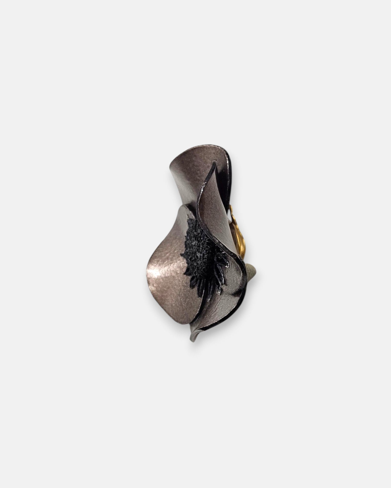 perspectiva de perfil de la pieza de autor, dejando ver la marcada curvatura de la flor, la base interior oscura de los pétalos y el mecanismo de pinza dorado trasero.